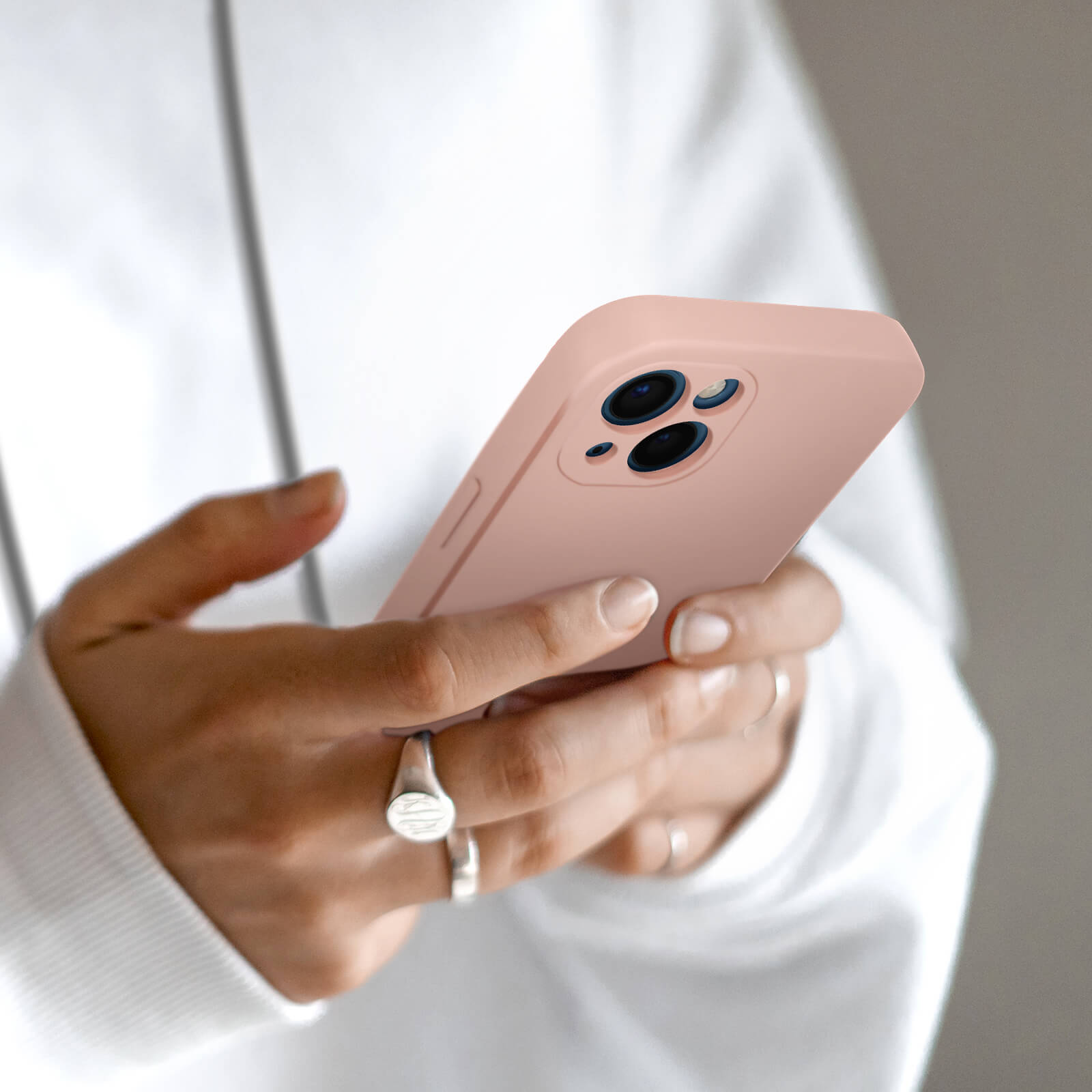 Une personne tient un smartphone rose à trois caméras.