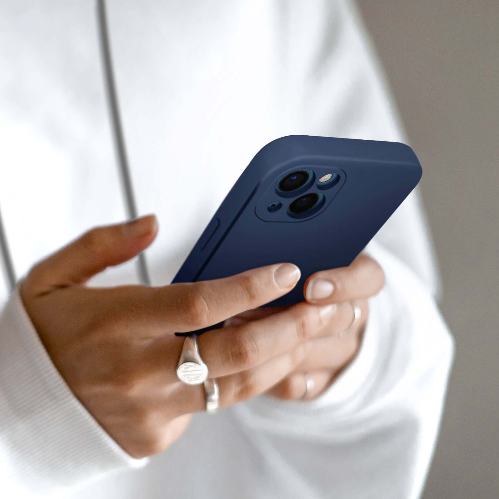 Hände halten ein dunkelblaues Handy mit Dreifachkamera.