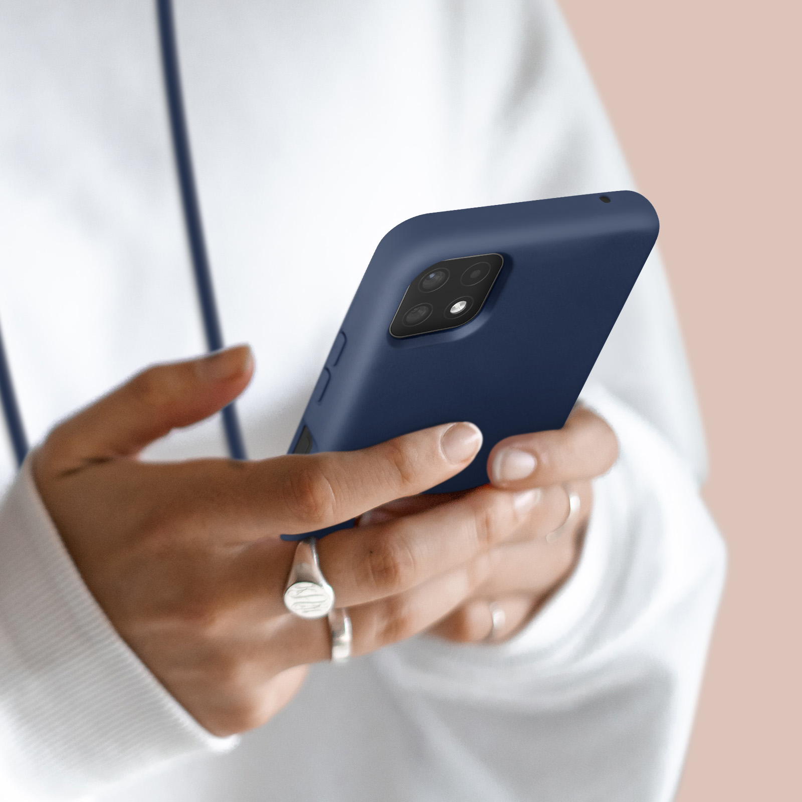 Personne en sweat à capuche blanc tenant un smartphone bleu foncé à quatre caméras.
