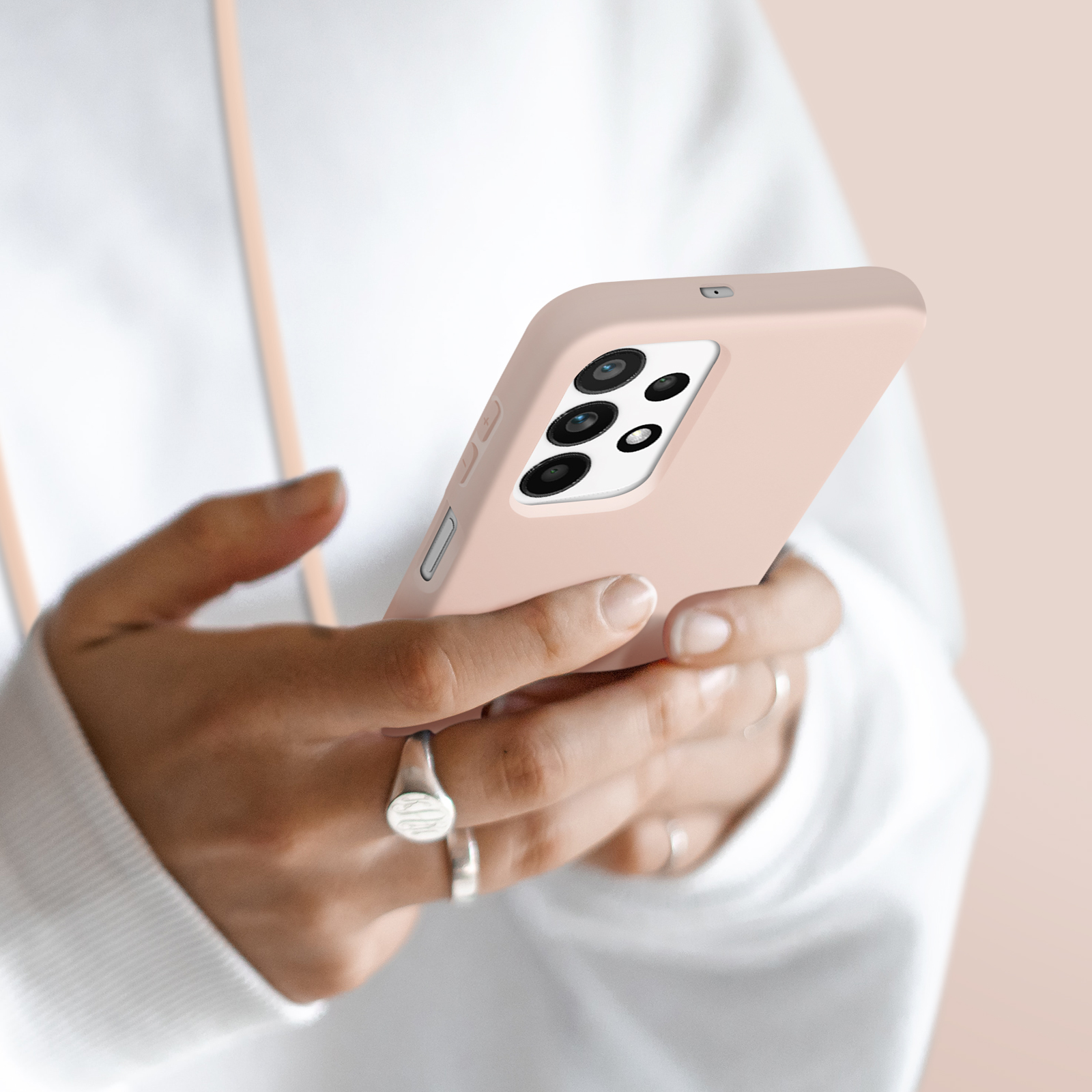 Eine Person hält ein hellrosa Smartphone mit einem Kameramodul mit vier Linsen.
