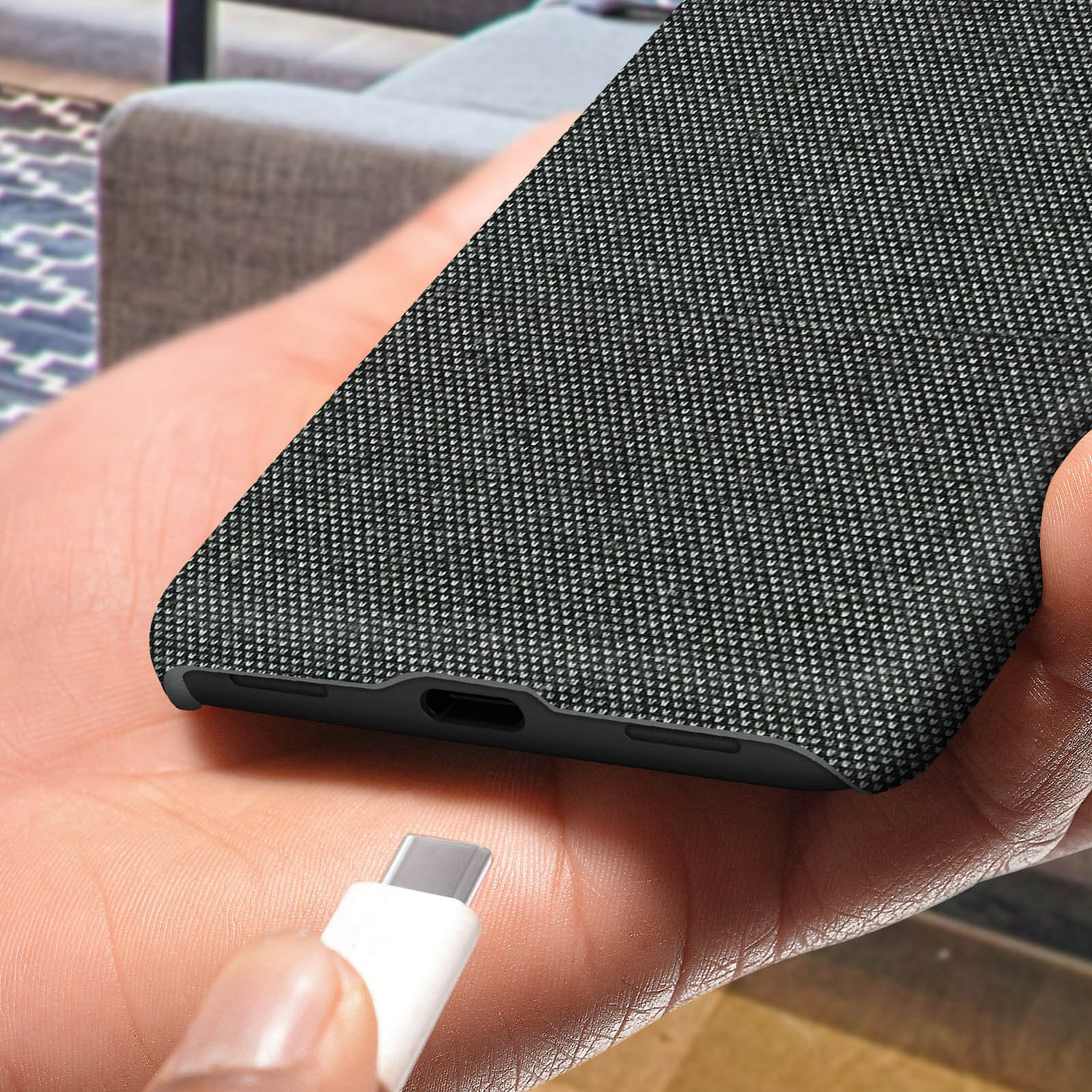 Een hand houdt een telefoon met grijze stoffen hoes vast, een USB-C-kabel nadert.