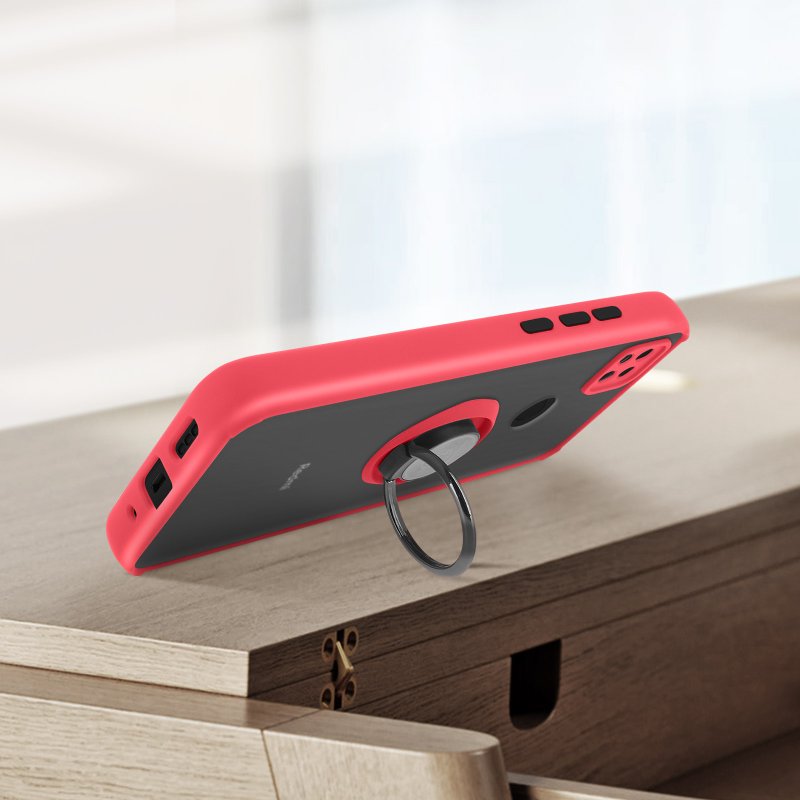 Een rood en zwart telefoonhoesje met ringstandaard ligt op een houten oppervlak.