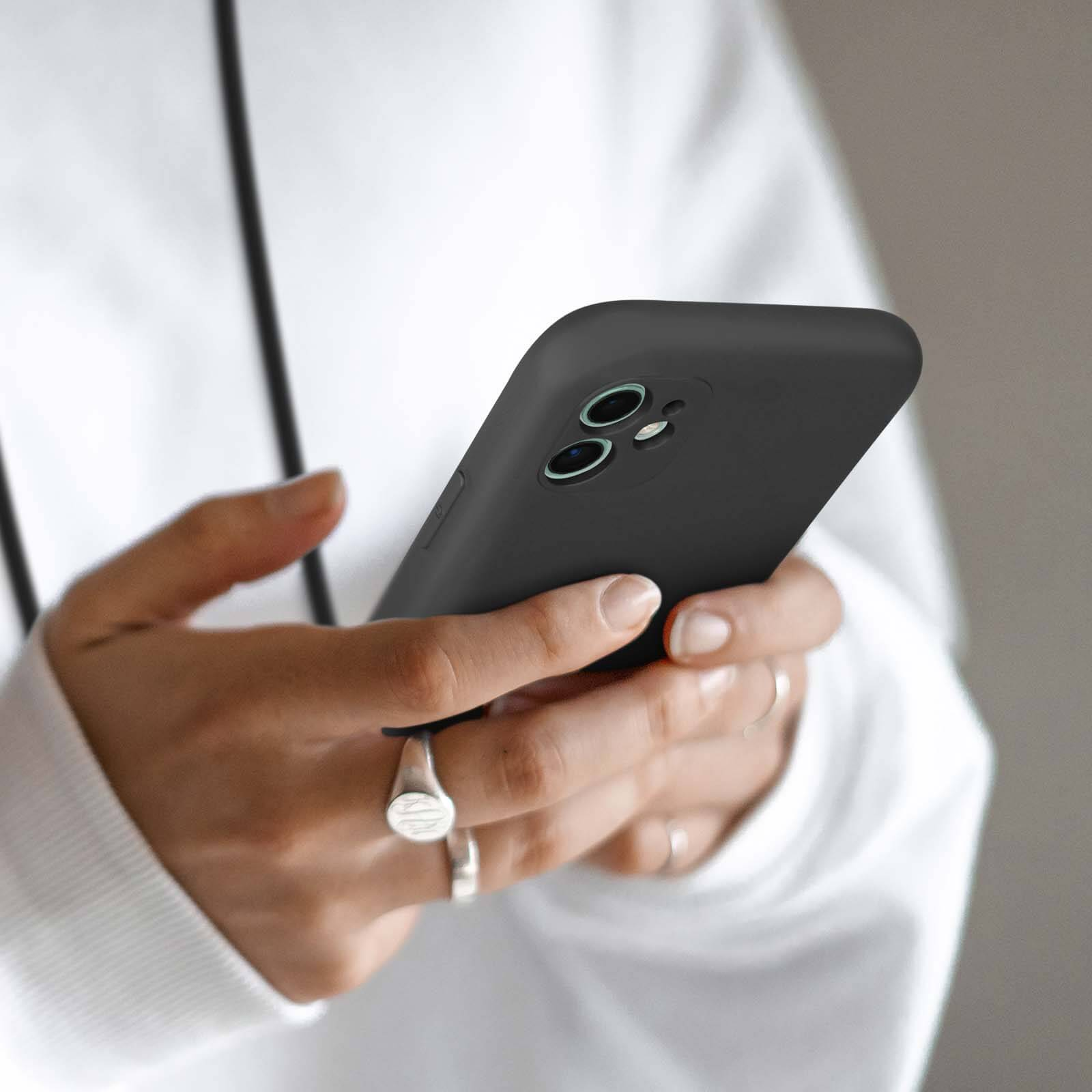 Mani che tengono uno smartphone nero con obiettivo a doppia fotocamera.