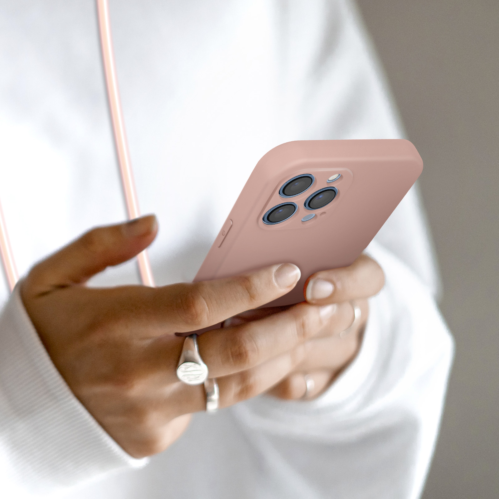 Mani che tengono un telefono rosa con tre obiettivi.