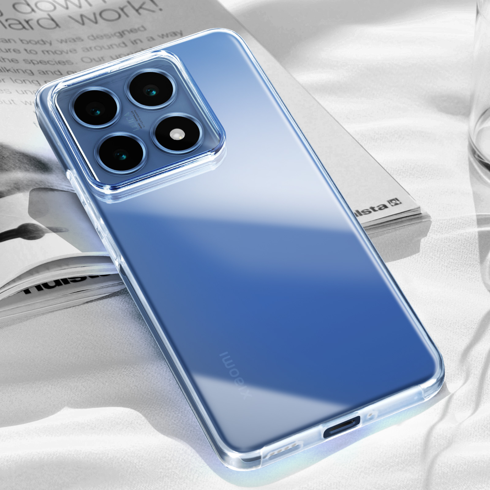 Une coque de téléphone transparente posée sur un livre avec tissu derrière.