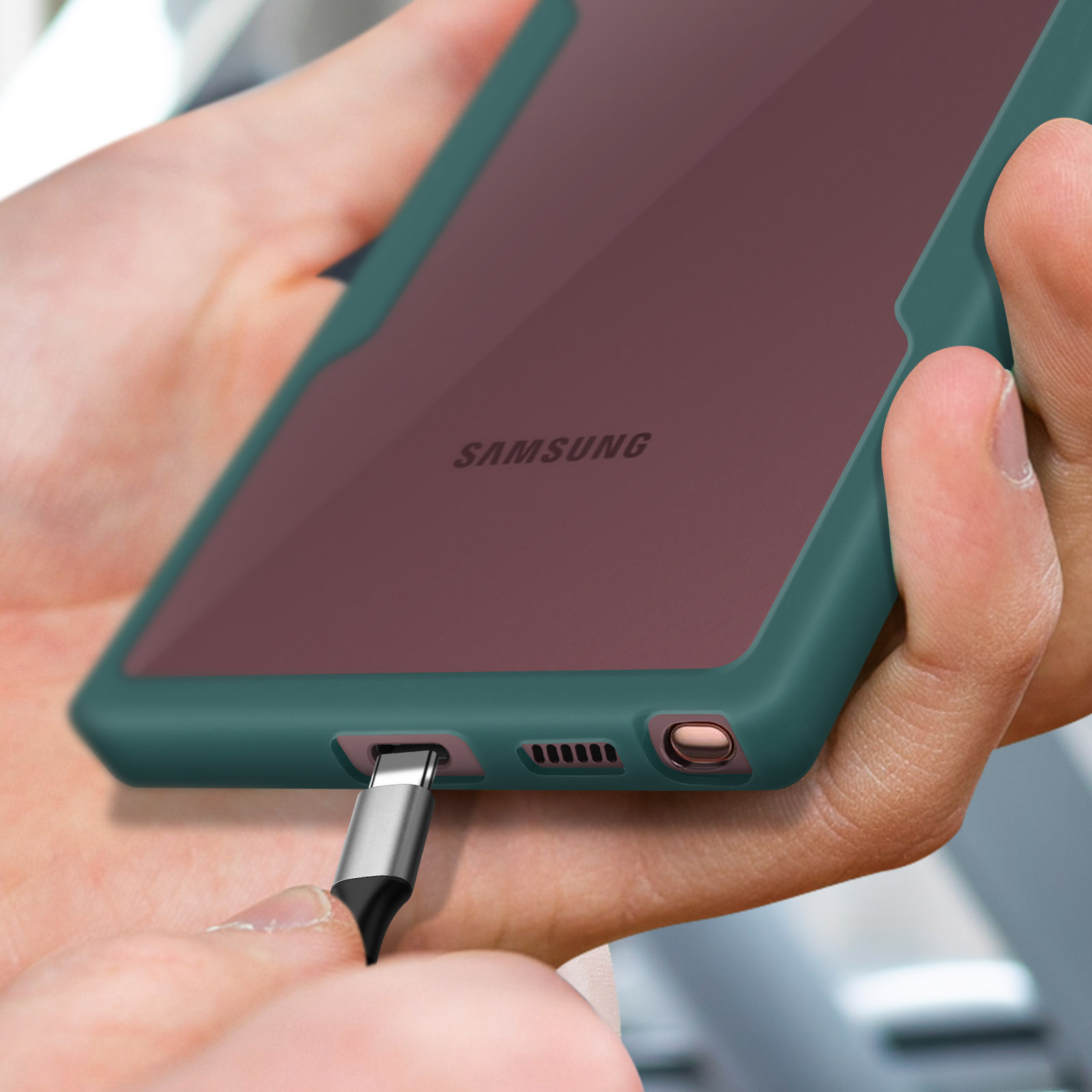 Una mano inserisce un cavo di ricarica in uno smartphone con custodia verde.