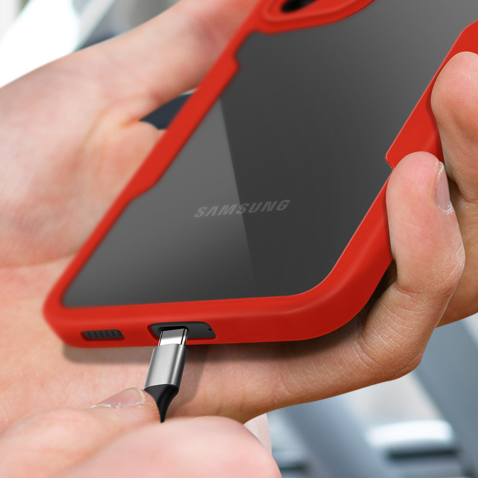 Handen steken een oplaadkabel in een rode Samsung telefoon.