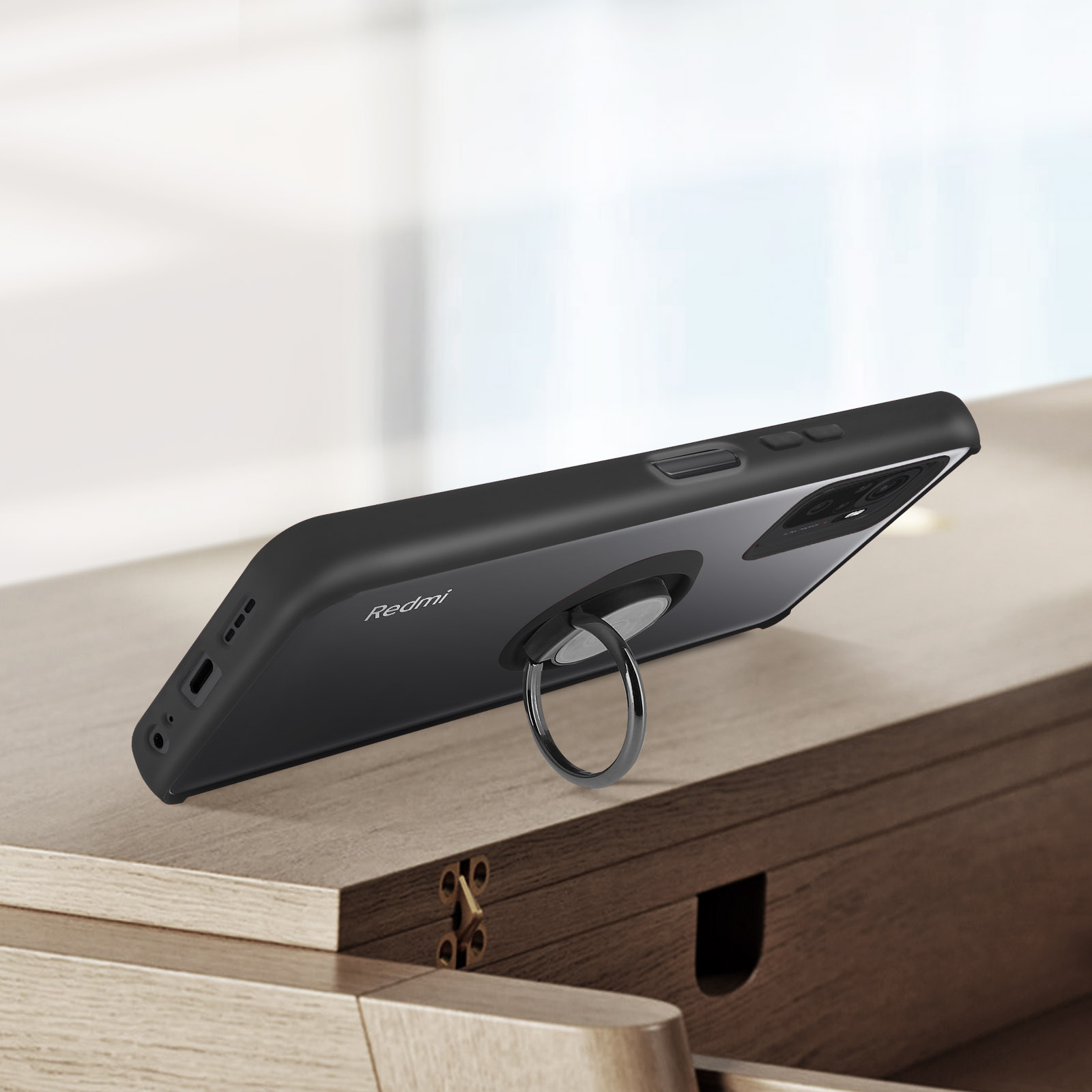 Custodia nera per telefono con anello portaoggetti su tavolo in legno.