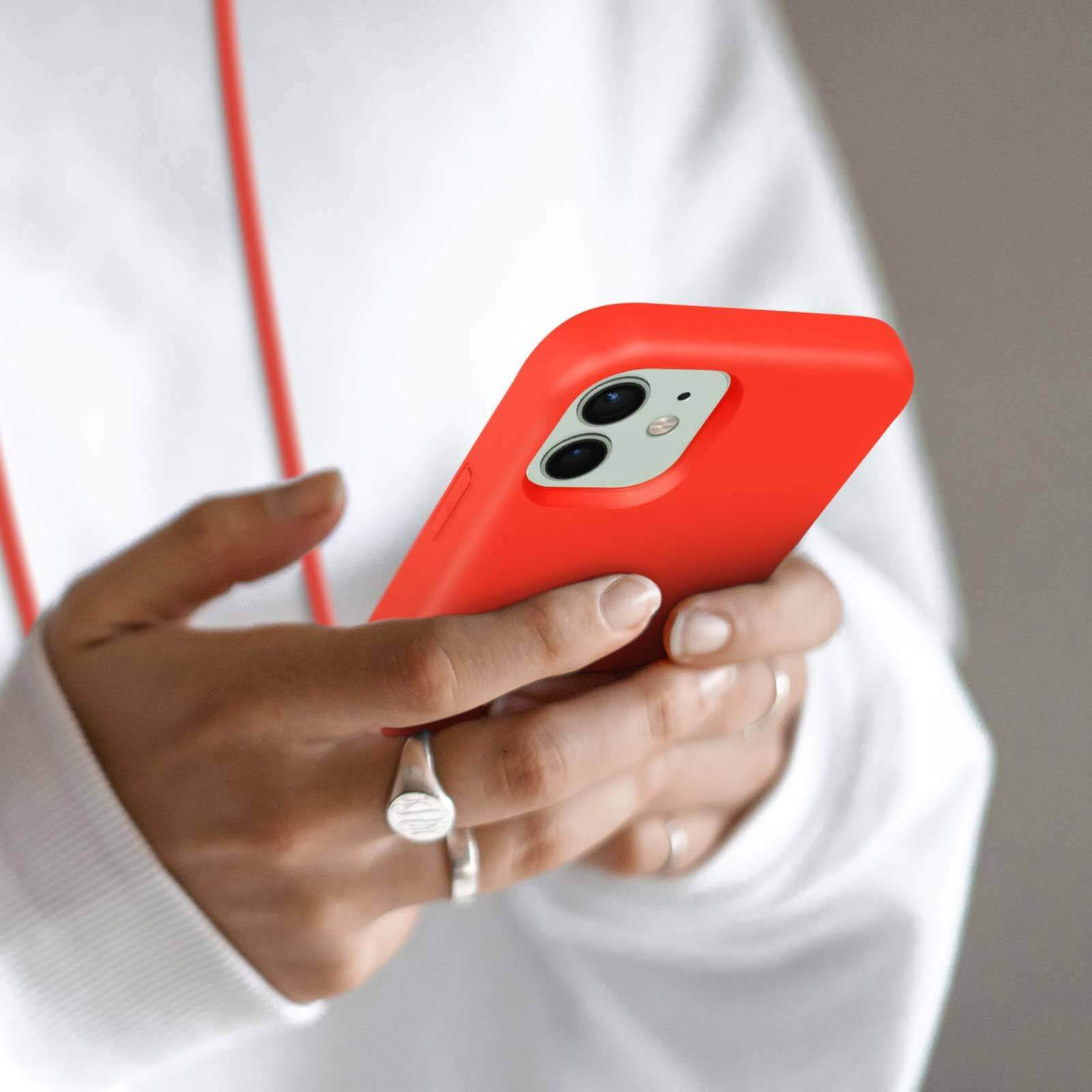 Eine Hand hält ein rotes iPhone mit zwei Kameras. Eine weiße Kapuze ist sichtbar.