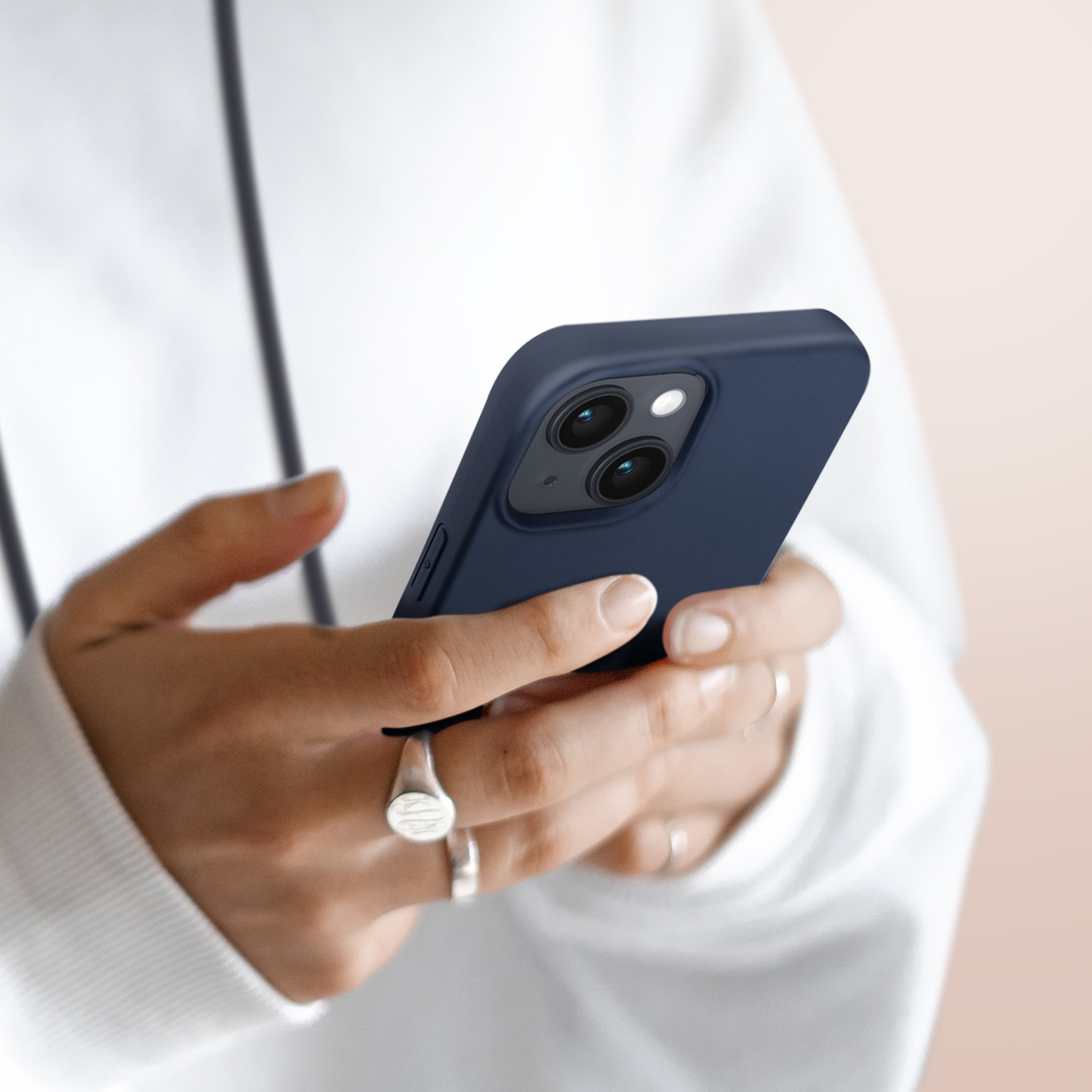 Een persoon houdt een donkerblauwe telefoon met twee camera's vast. Ze draagt ringen.