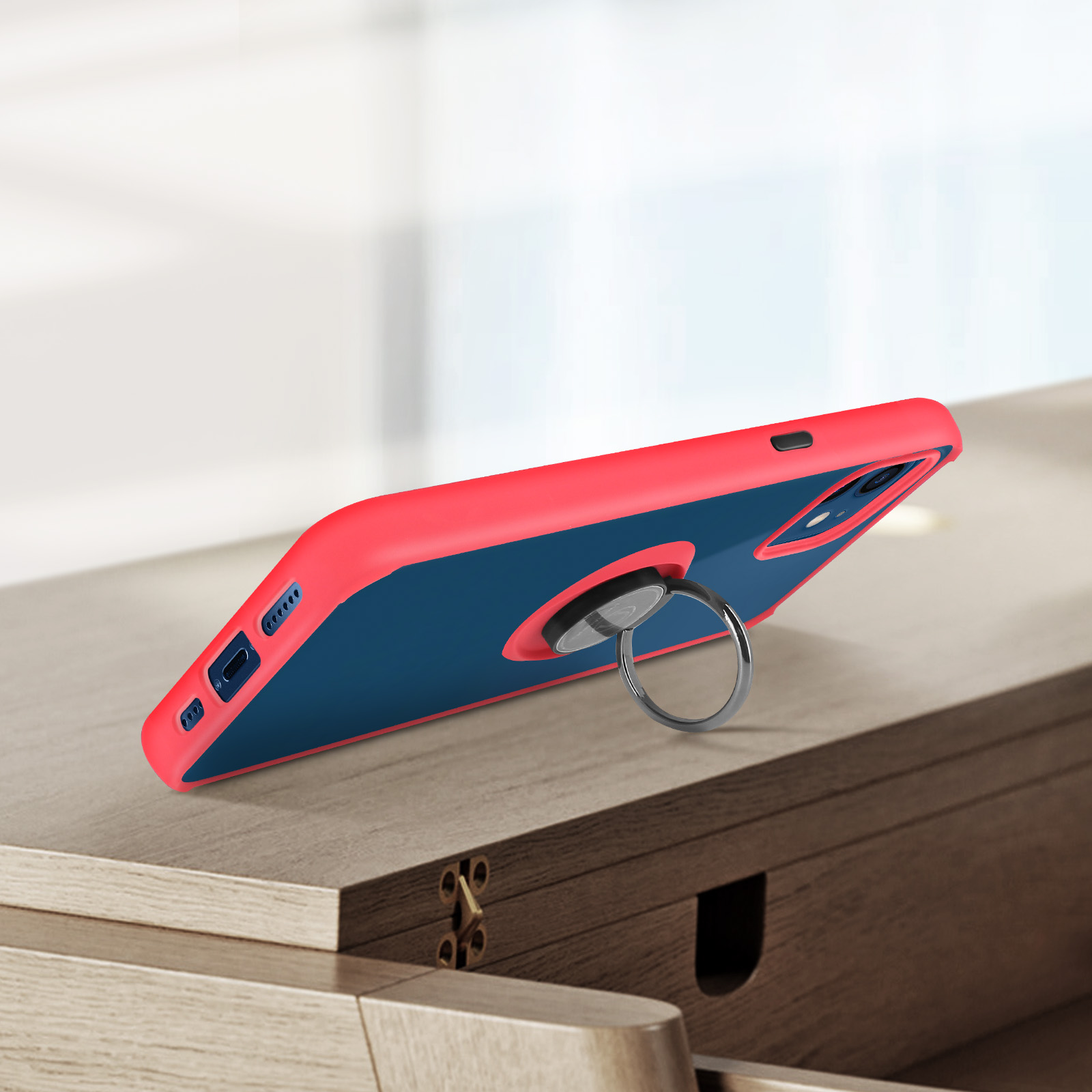 Una cover per telefono rossa e blu con anello poggia su un tavolo di legno.