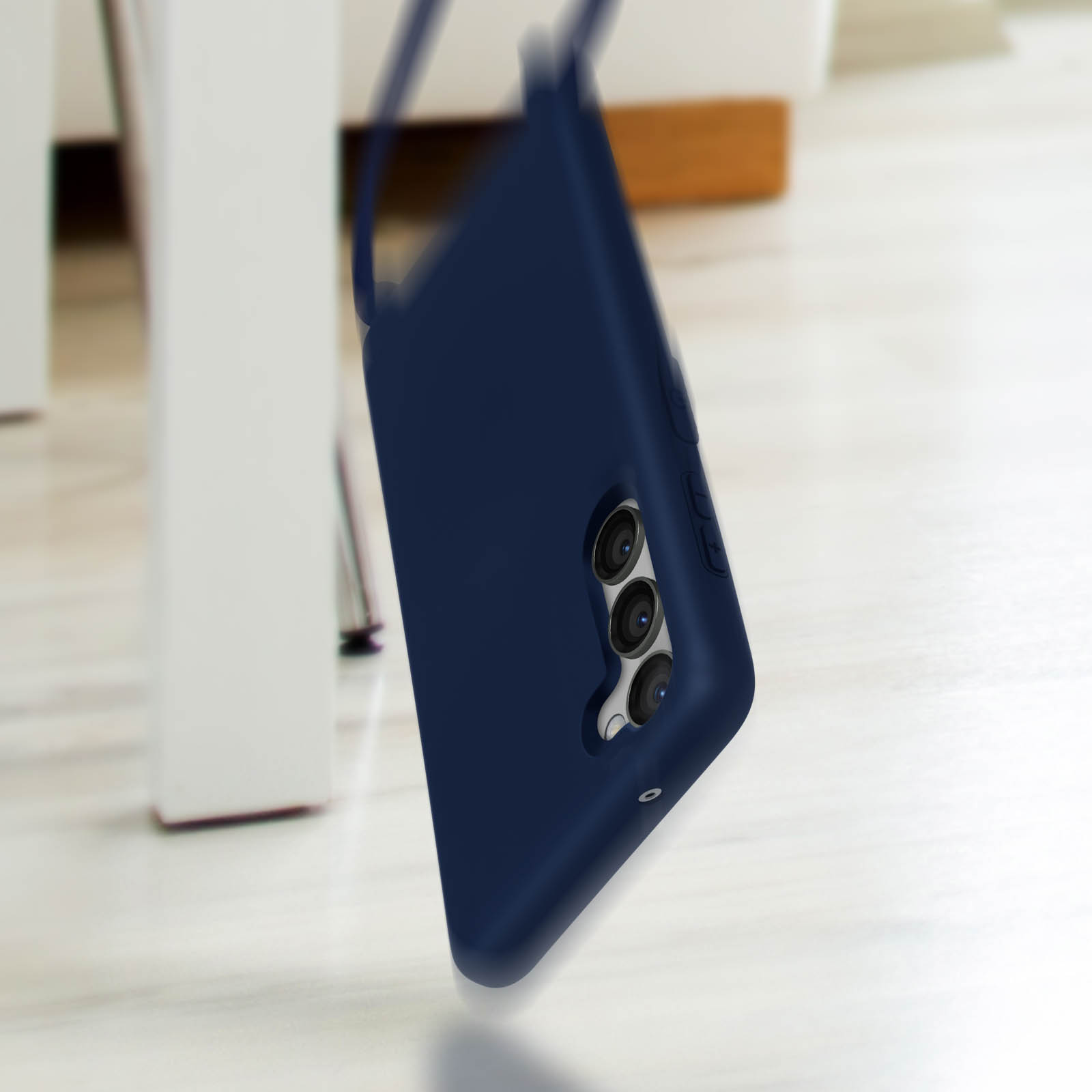 Coque de téléphone bleu foncé avec trois caméras tombant, arrière-plan flou.