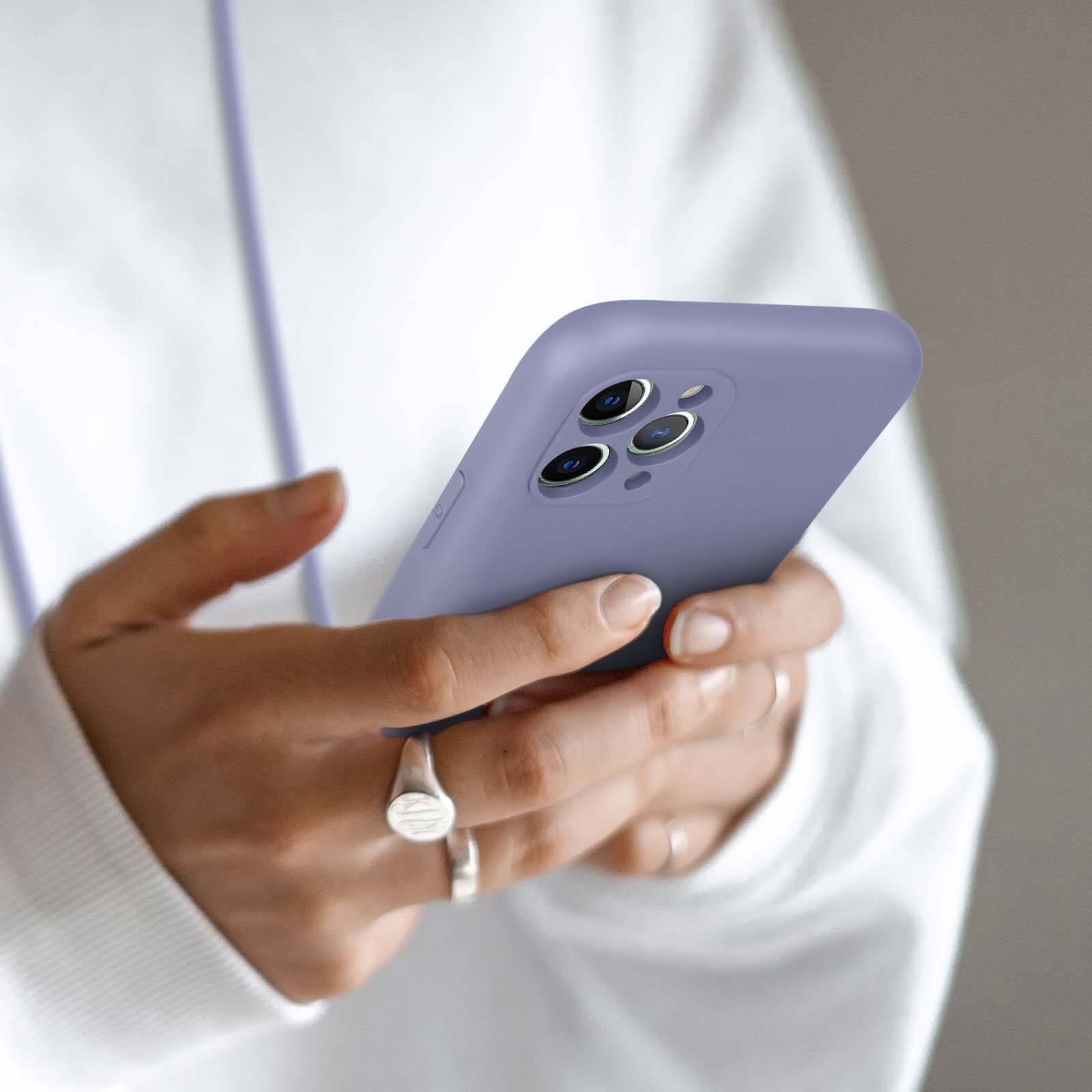 Een persoon houdt een paars iPhone met drie camera's vast.