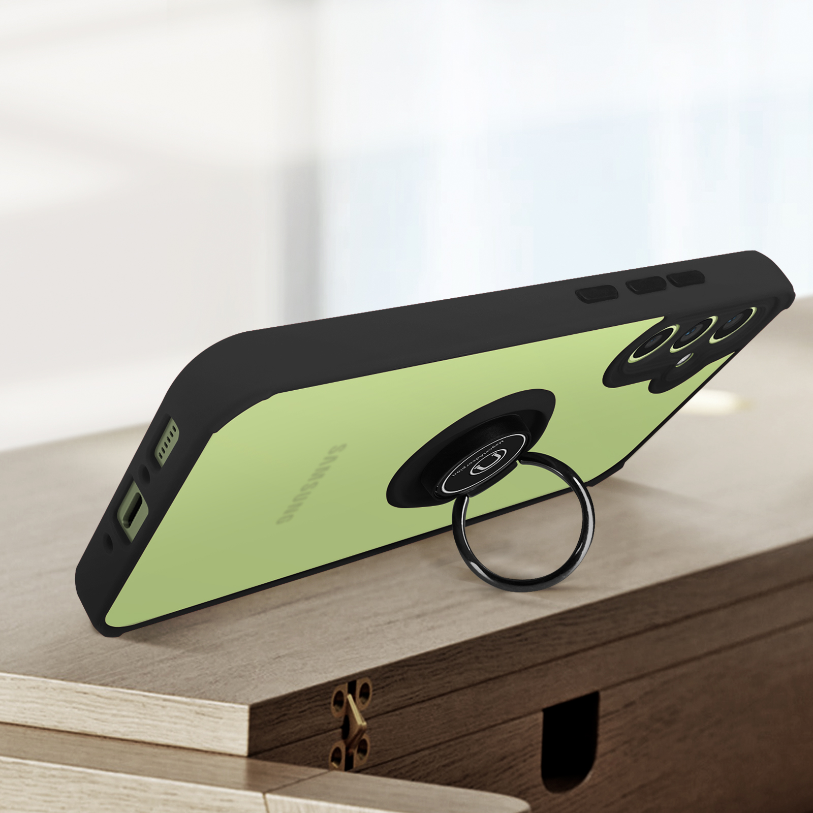 Un telefono verde chiaro con cornice nera e anello portaoggetti su tavolo legno.
