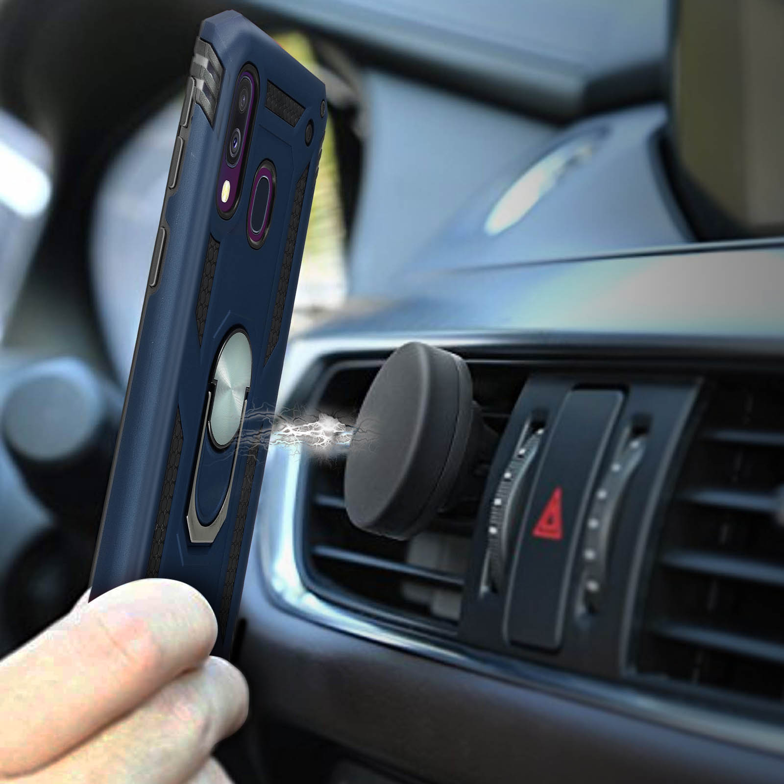 Una mano tiene un telefono blu scuro con anello vicino a una presa d'aria per auto.