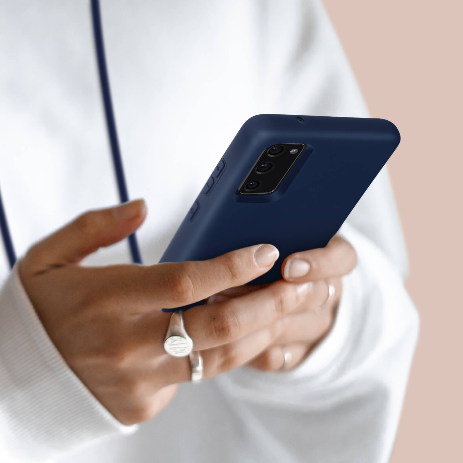 Gros plan d'une personne en sweat à capuche blanc tenant un smartphone bleu foncé.