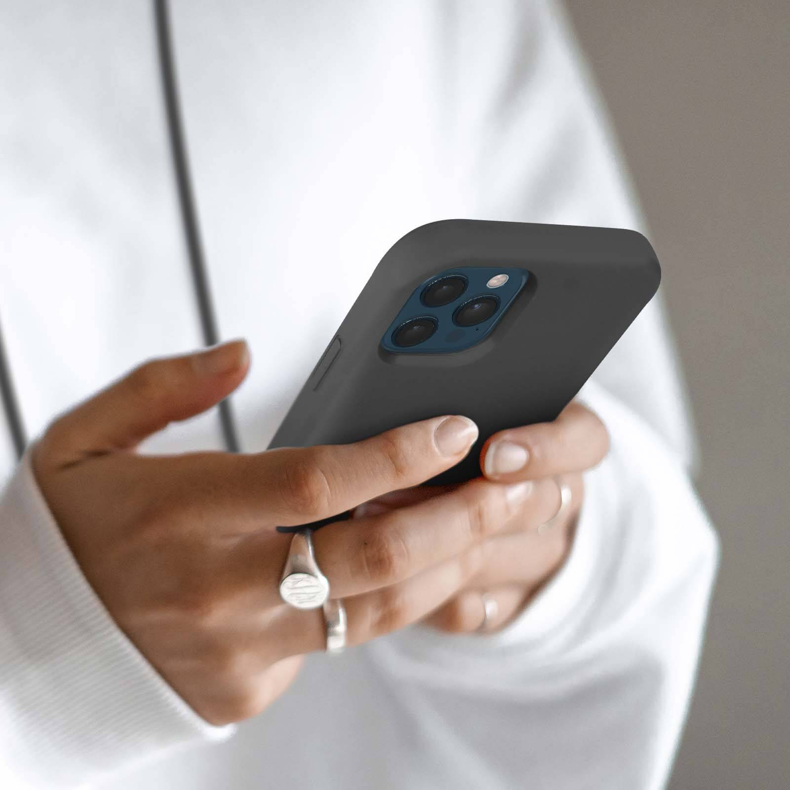 Close-up van een persoon die een donkere smartphone vasthoudt.