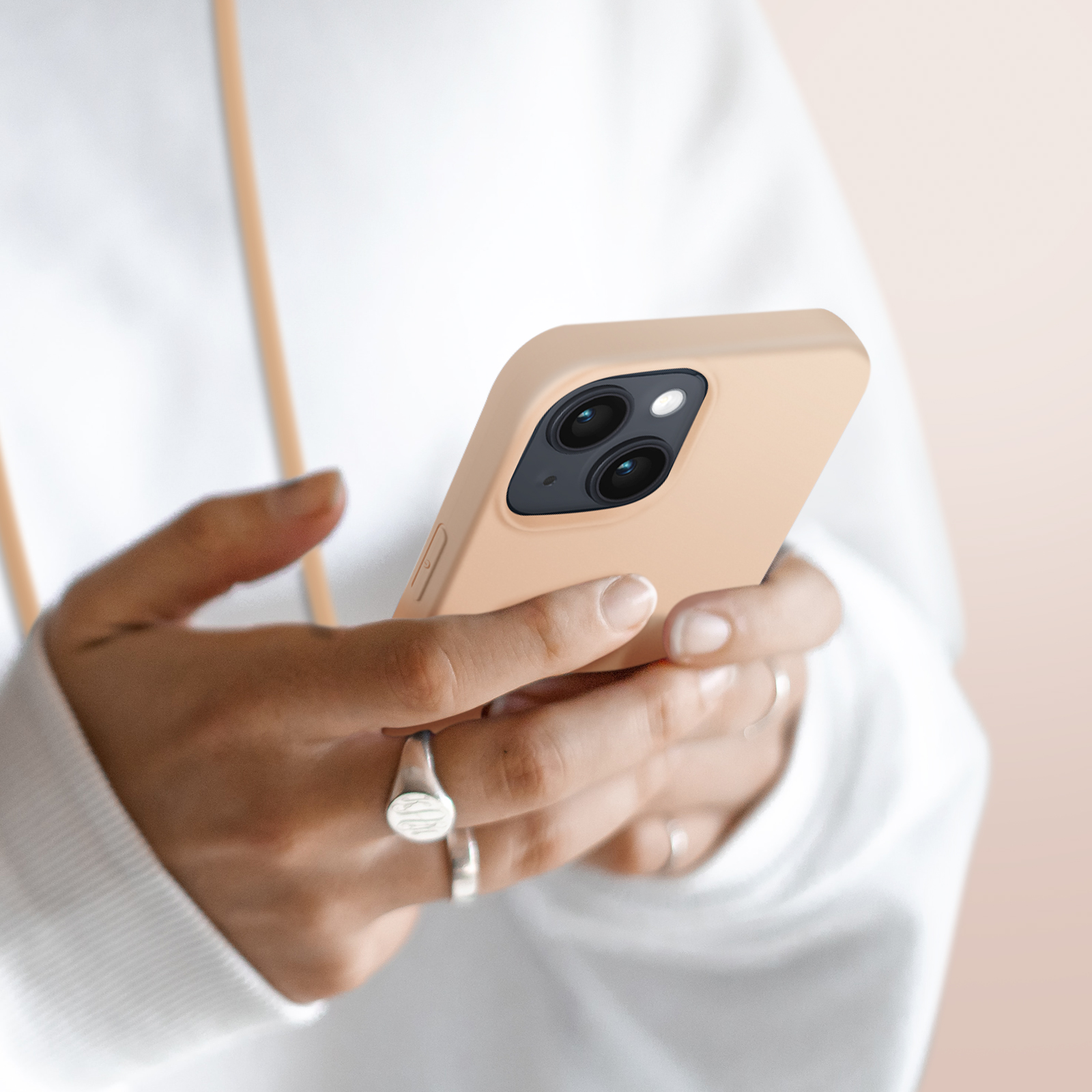Een persoon in een witte hoodie gebruikt een lichtbruine telefoon met twee camera's.