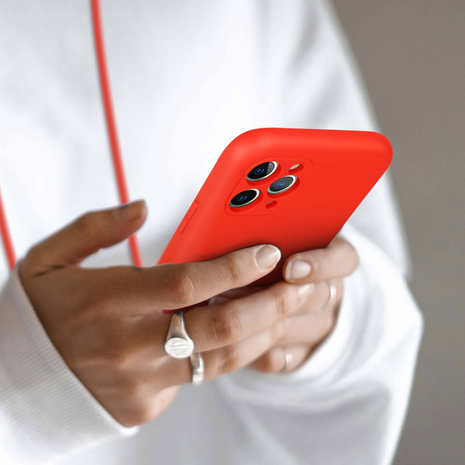 Personne tenant un smartphone rouge vif avec trois objectifs.