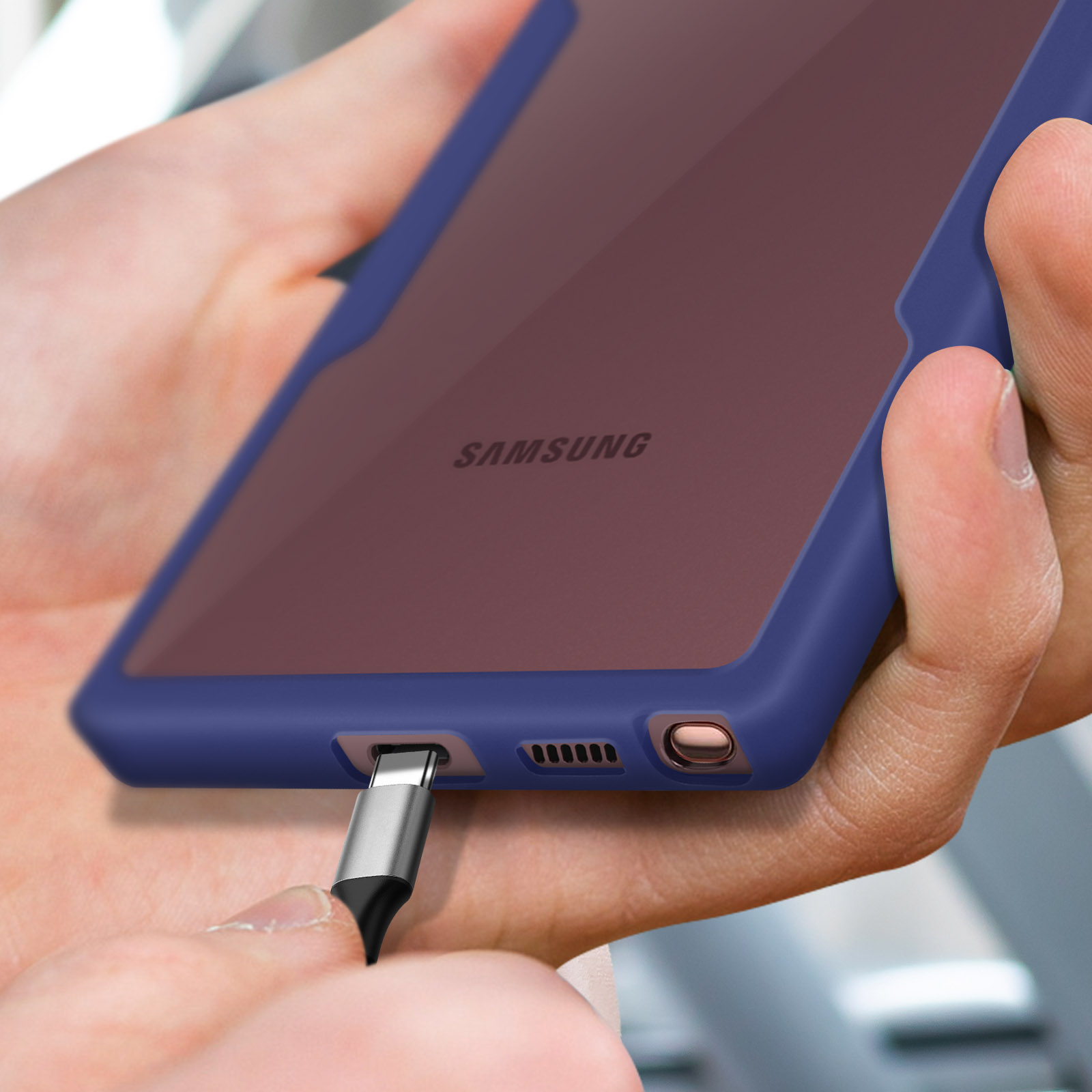 Una mano tiene un telefono Samsung blu mentre viene inserito un cavo di ricarica.