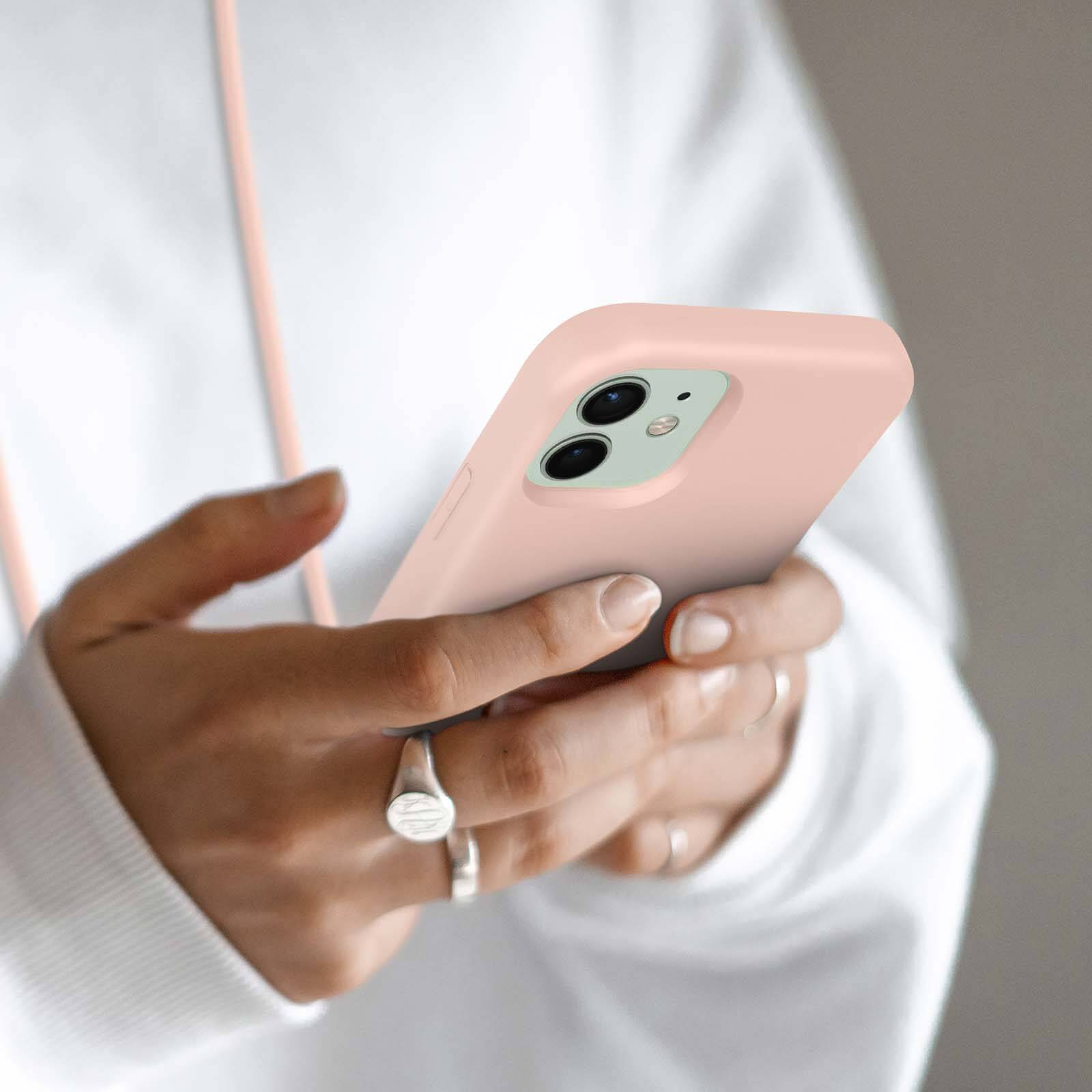 Hände halten ein rosa Smartphone mit zwei Kameras.