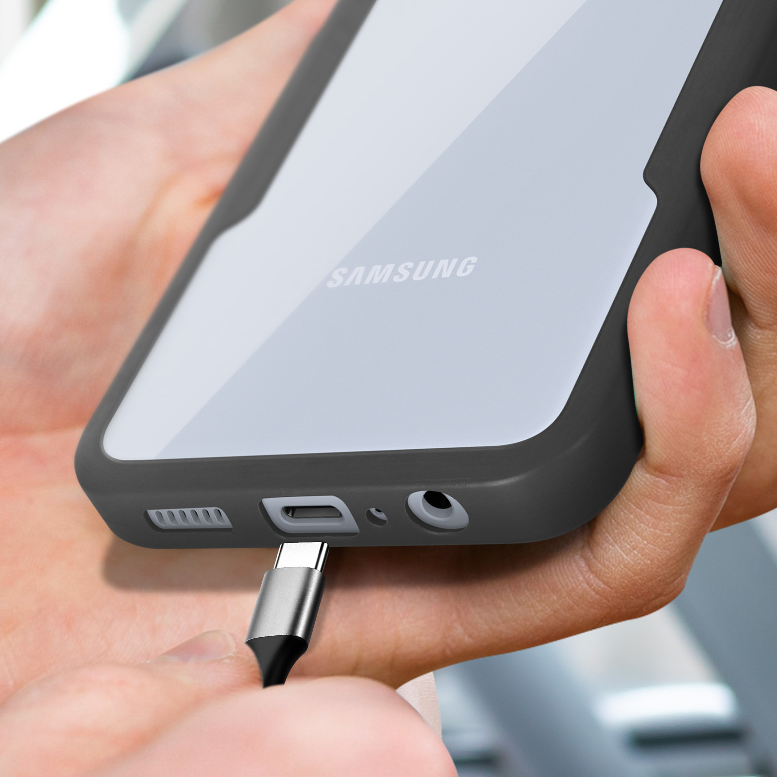 Een USB-C kabel wordt aangesloten op een Samsung telefoon die door twee handen wordt vastgehouden.