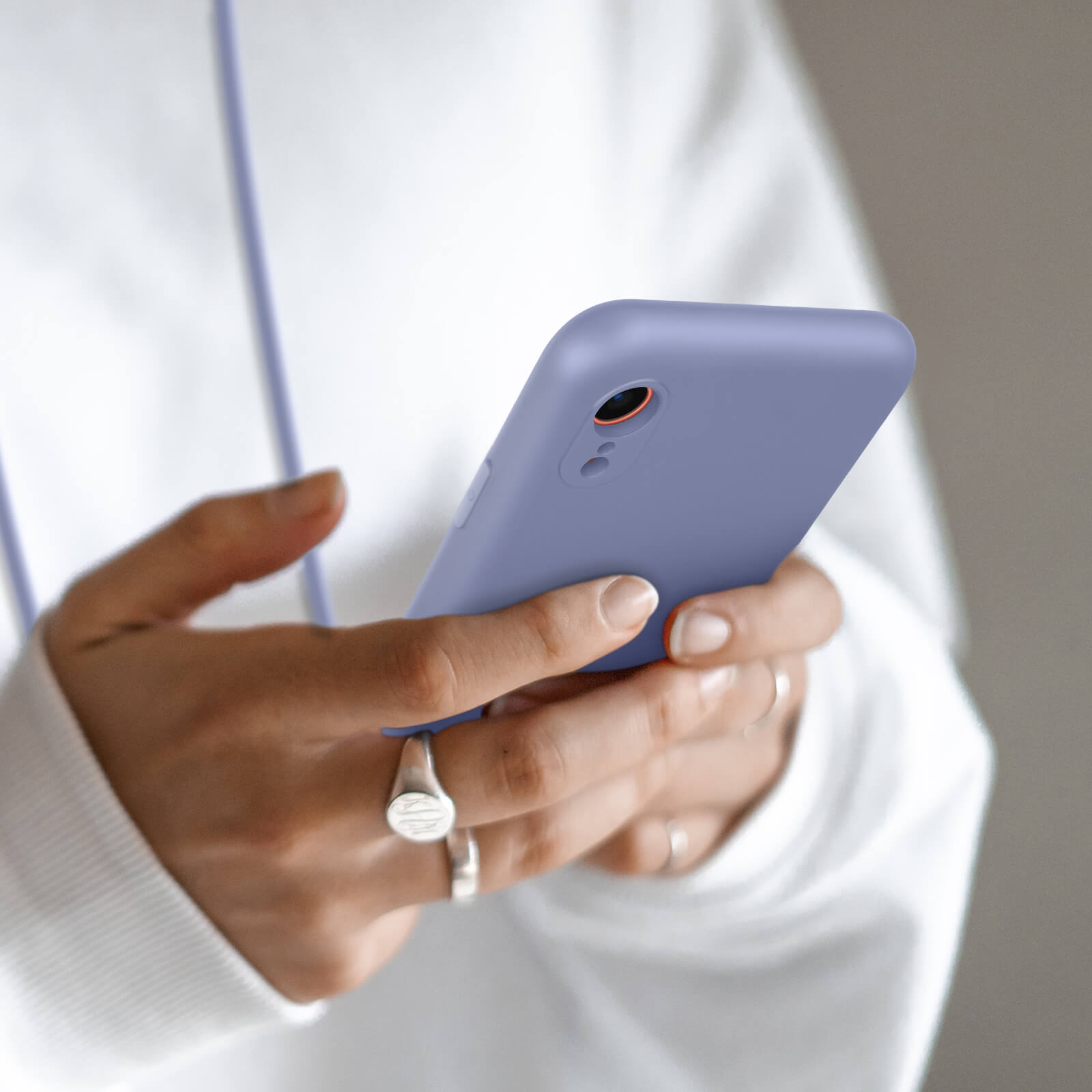 Une personne tient un smartphone violet, portant une bague et une chevalière.