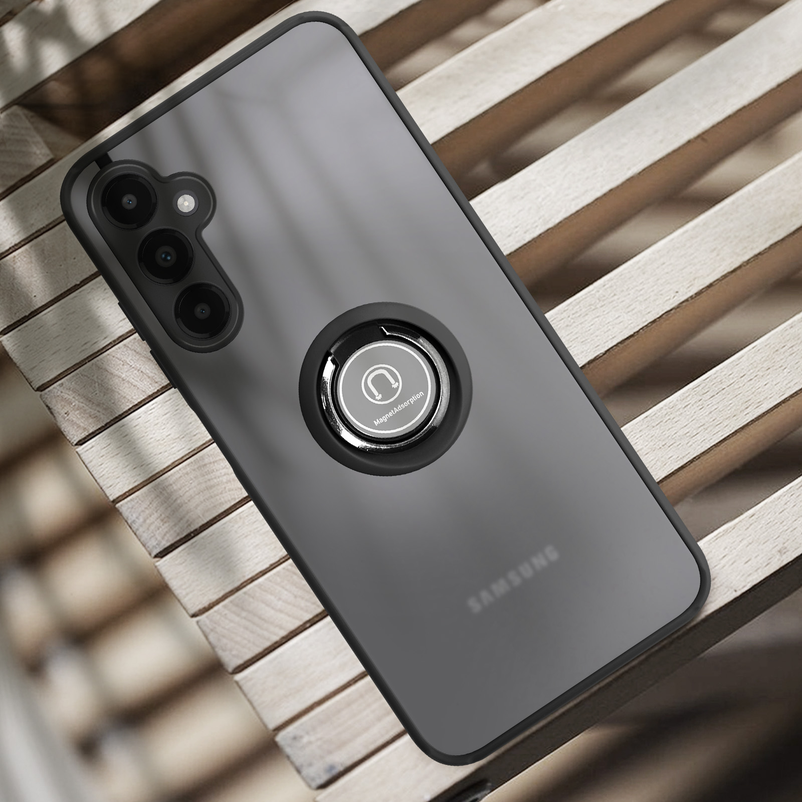 Un telefono Samsung grigio scuro con anello portaoggetti su superficie in legno.