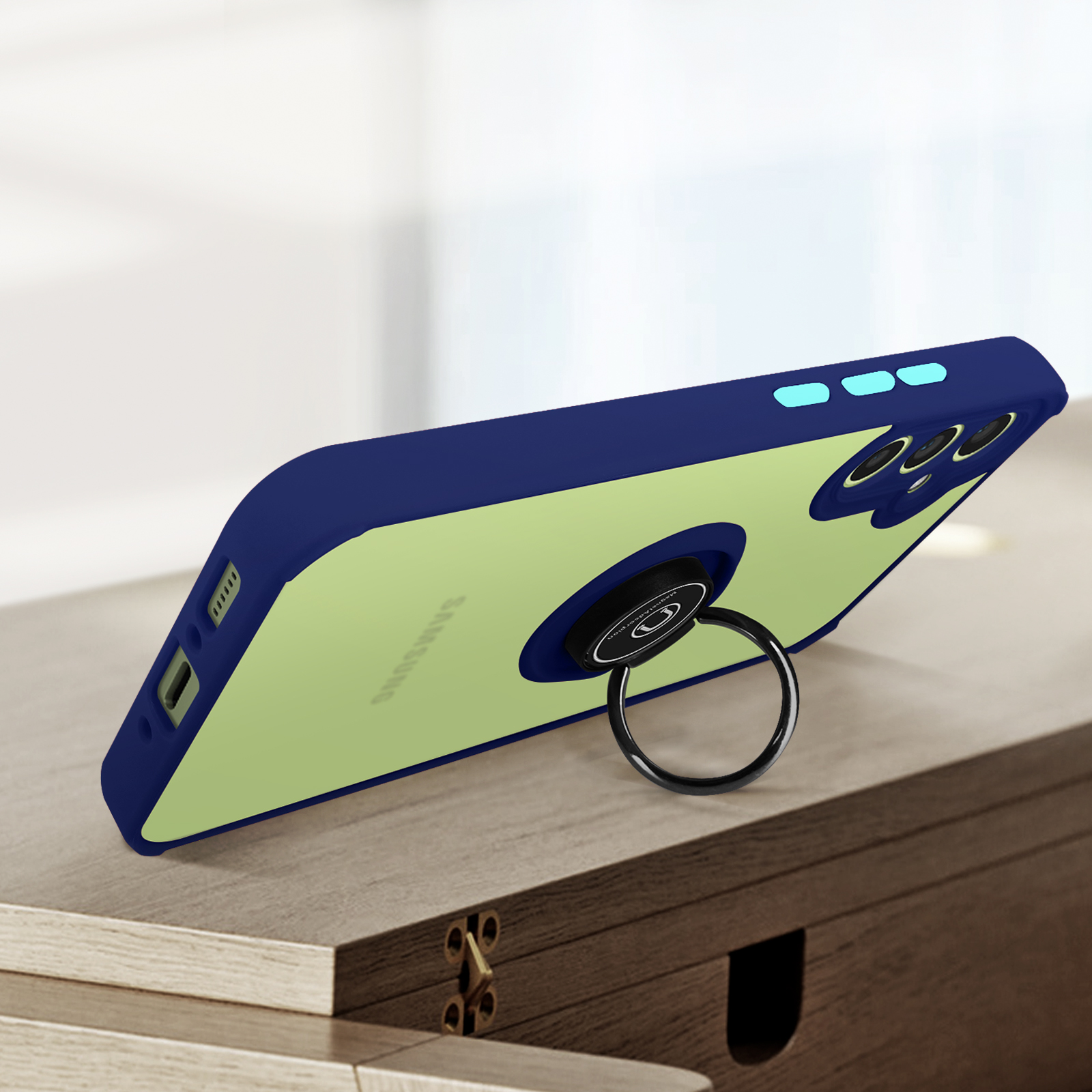 Un telefono verde chiaro bordato di blu con anello portaoggetti poggia su un tavolo di legno.