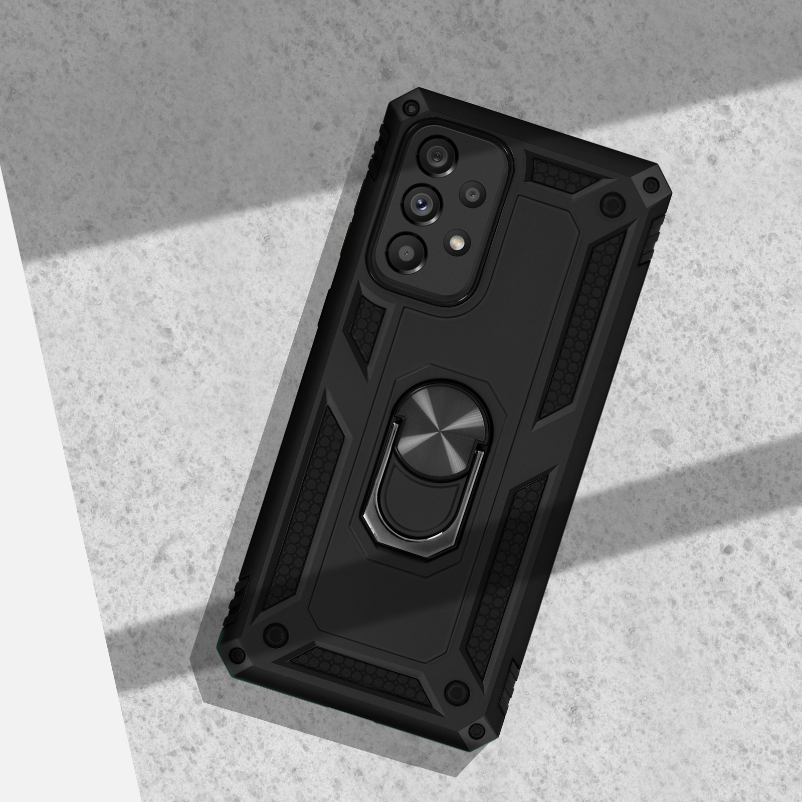 Cover nera per telefono con anello porta-dita e foro fotocamera su cemento.