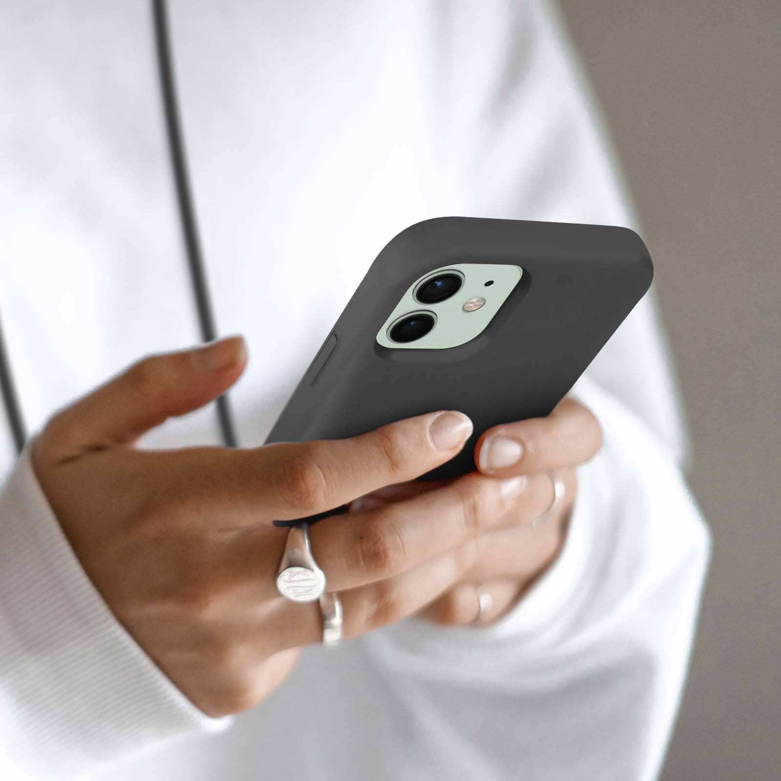 Person hält dunkles Smartphone mit zwei Kameras.