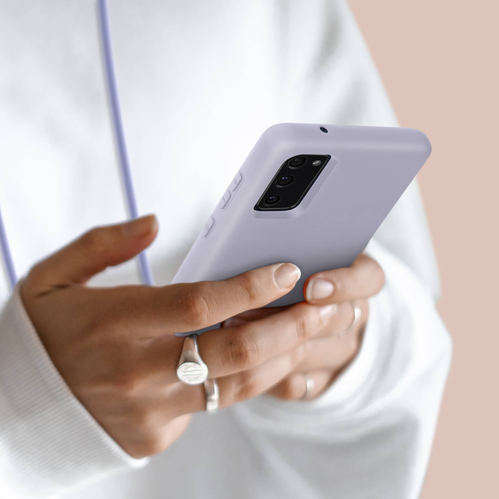 Une personne tient un smartphone violet avec triple caméra arrière.