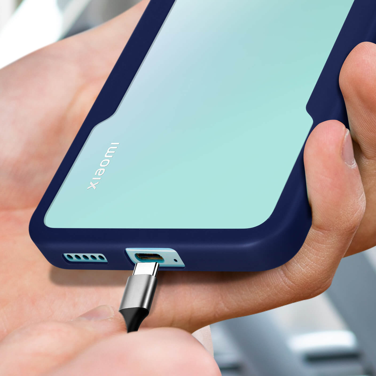 Mains branchant un câble USB-C à un téléphone bleu et vert clair.