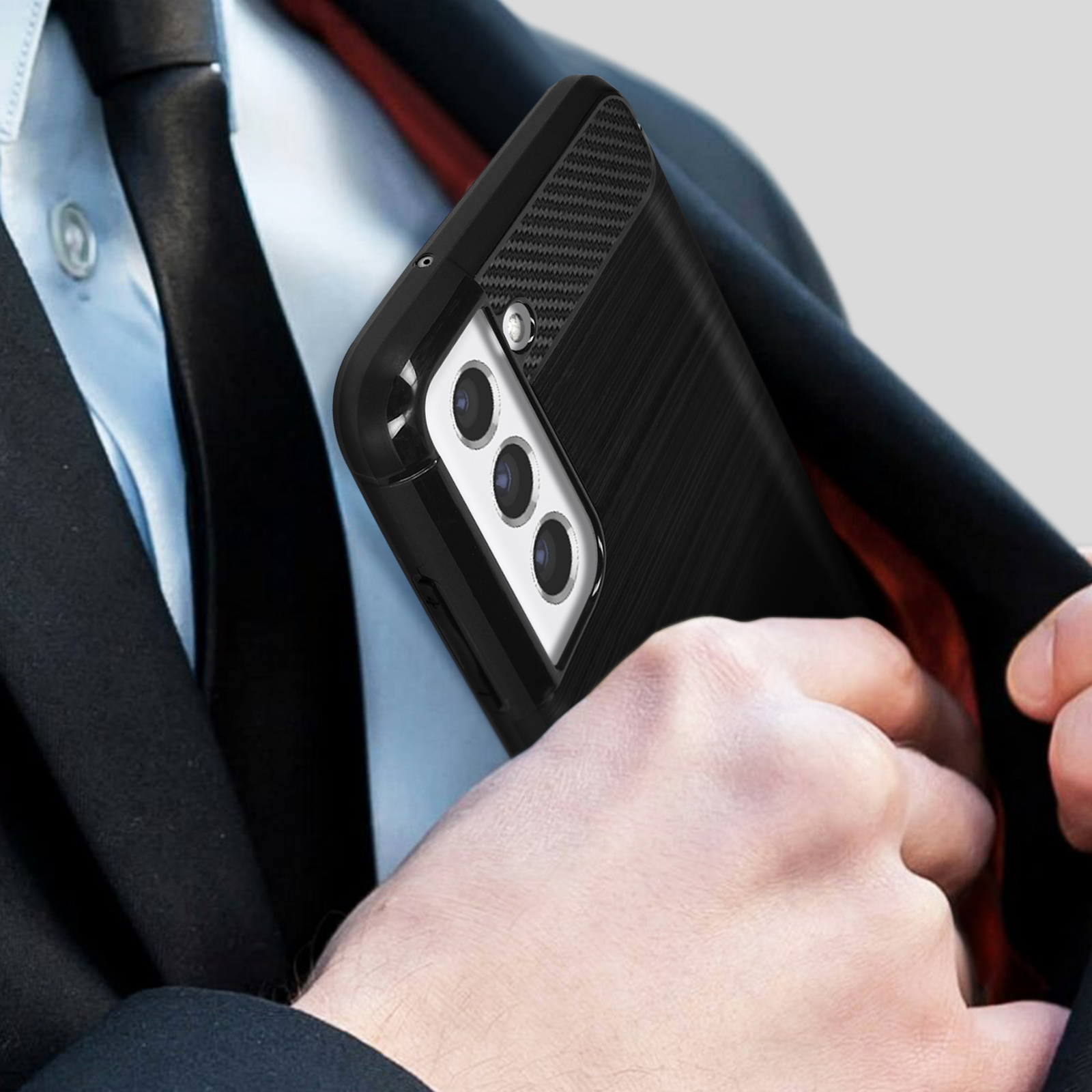 Un uomo infila un telefono nero con tre fotocamere nella tasca del vestito.