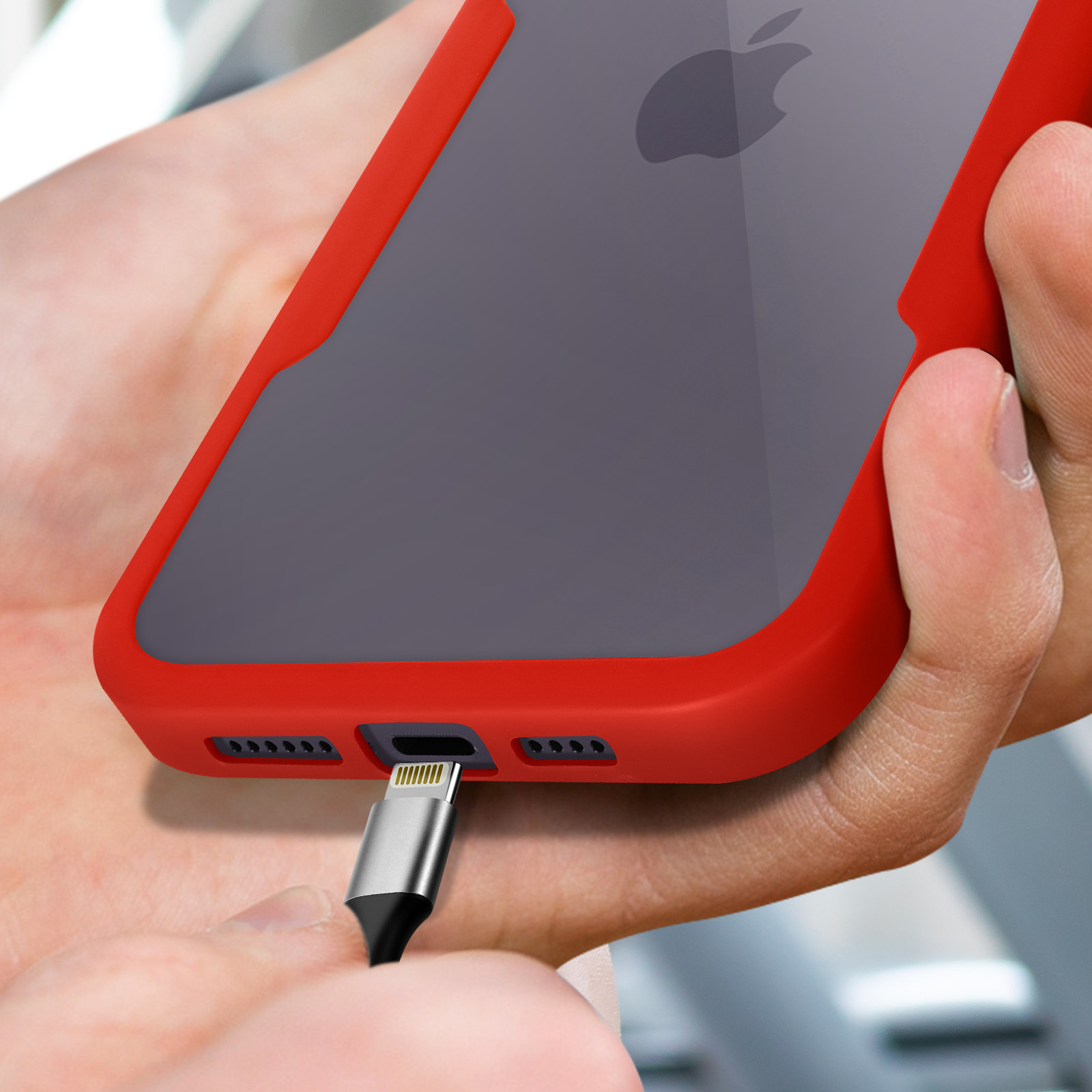 Een hand sluit een oplaadkabel aan op een iPhone met rode hoes.