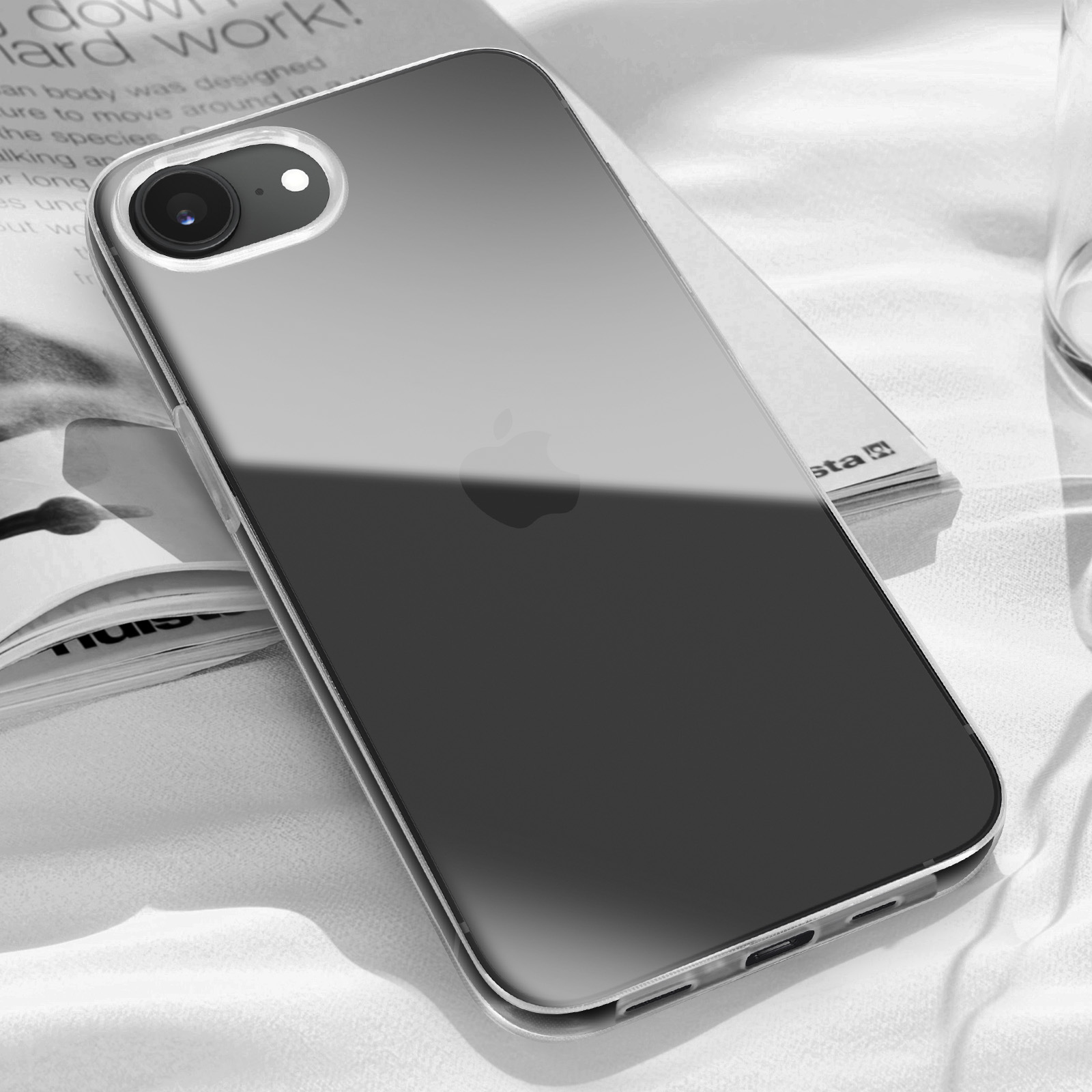 Un téléphone transparent avec logo Apple sur un livre.