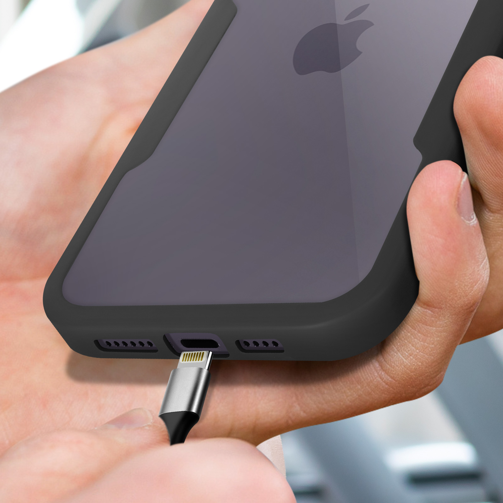 Une main branche un câble de chargement argenté sur un iPhone sombre.