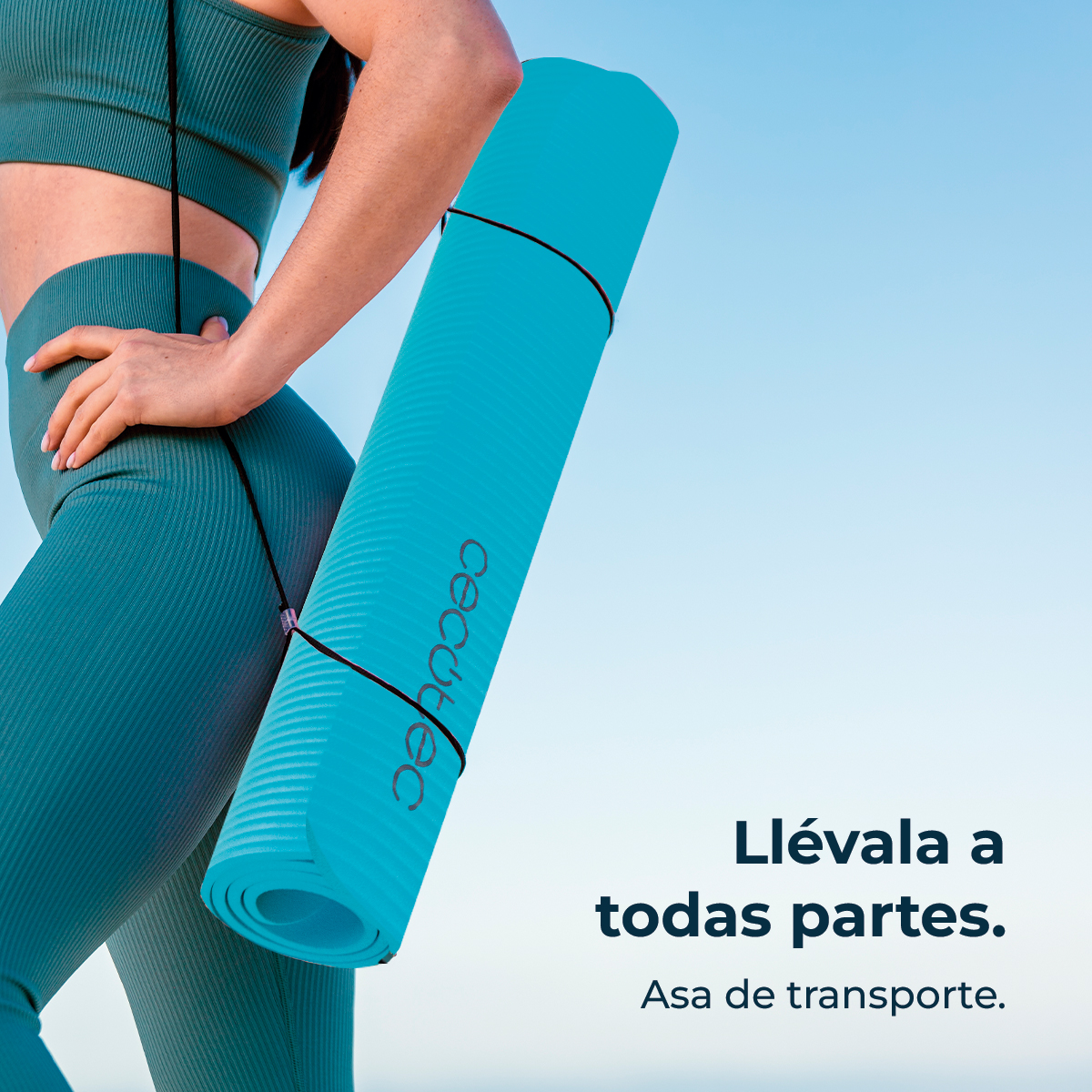 Una donna in abbigliamento sportivo turchese tiene un tappetino yoga turchese arrotolato.