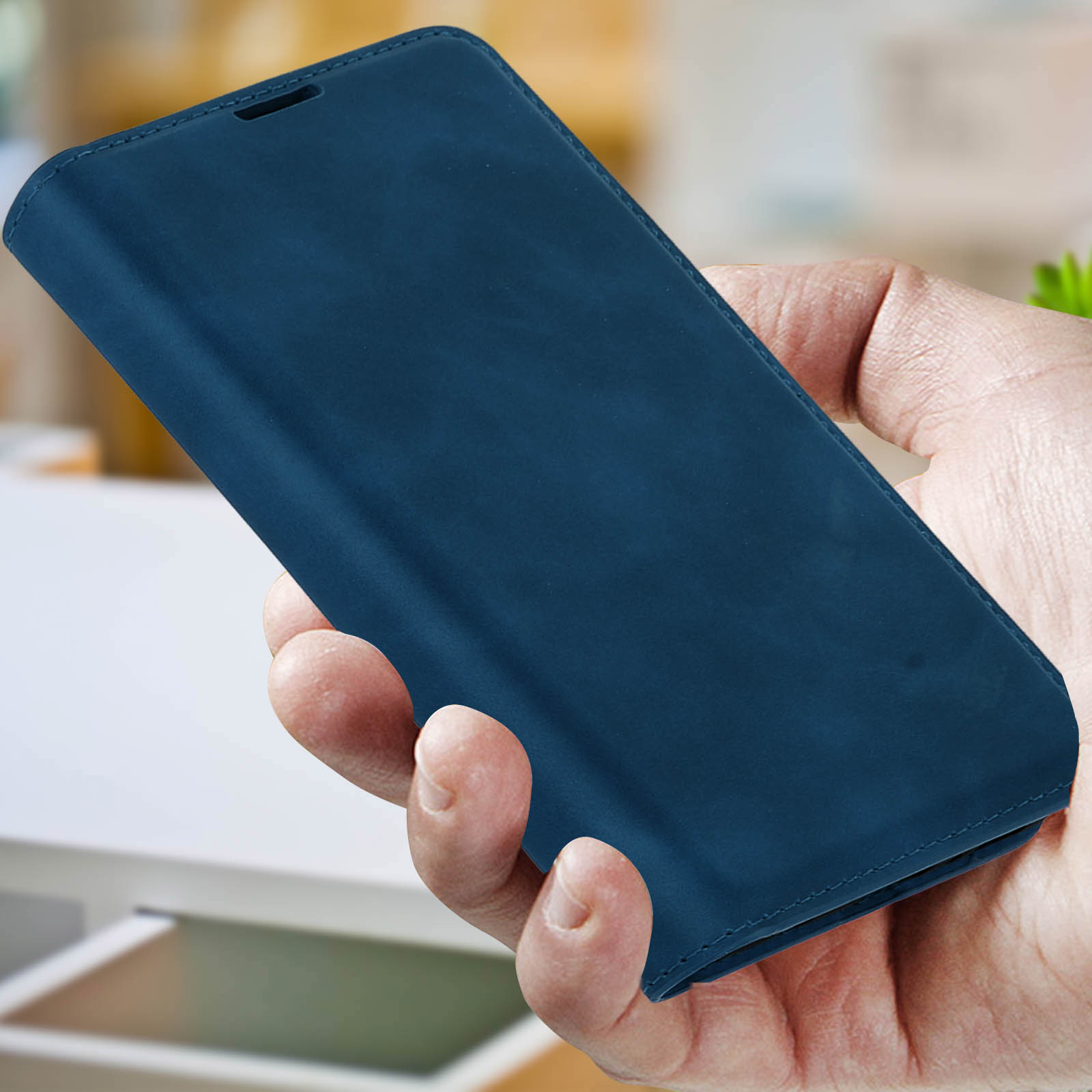 Una mano tiene una custodia blu scuro per telefono. Lo sfondo è sfocato.