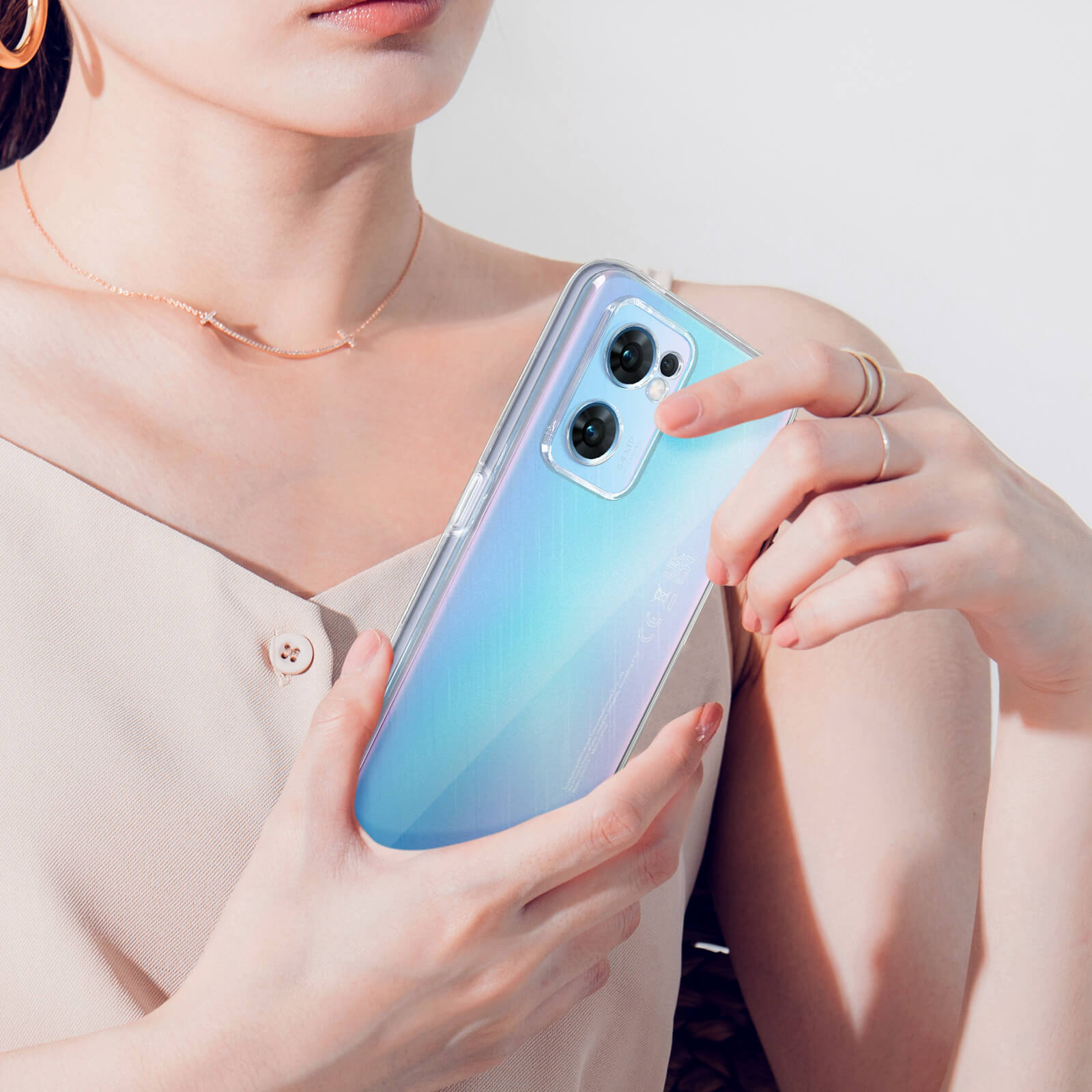 Une femme tient un téléphone transparent à dégradé bleu-vert. Deux caméras sont visibles.