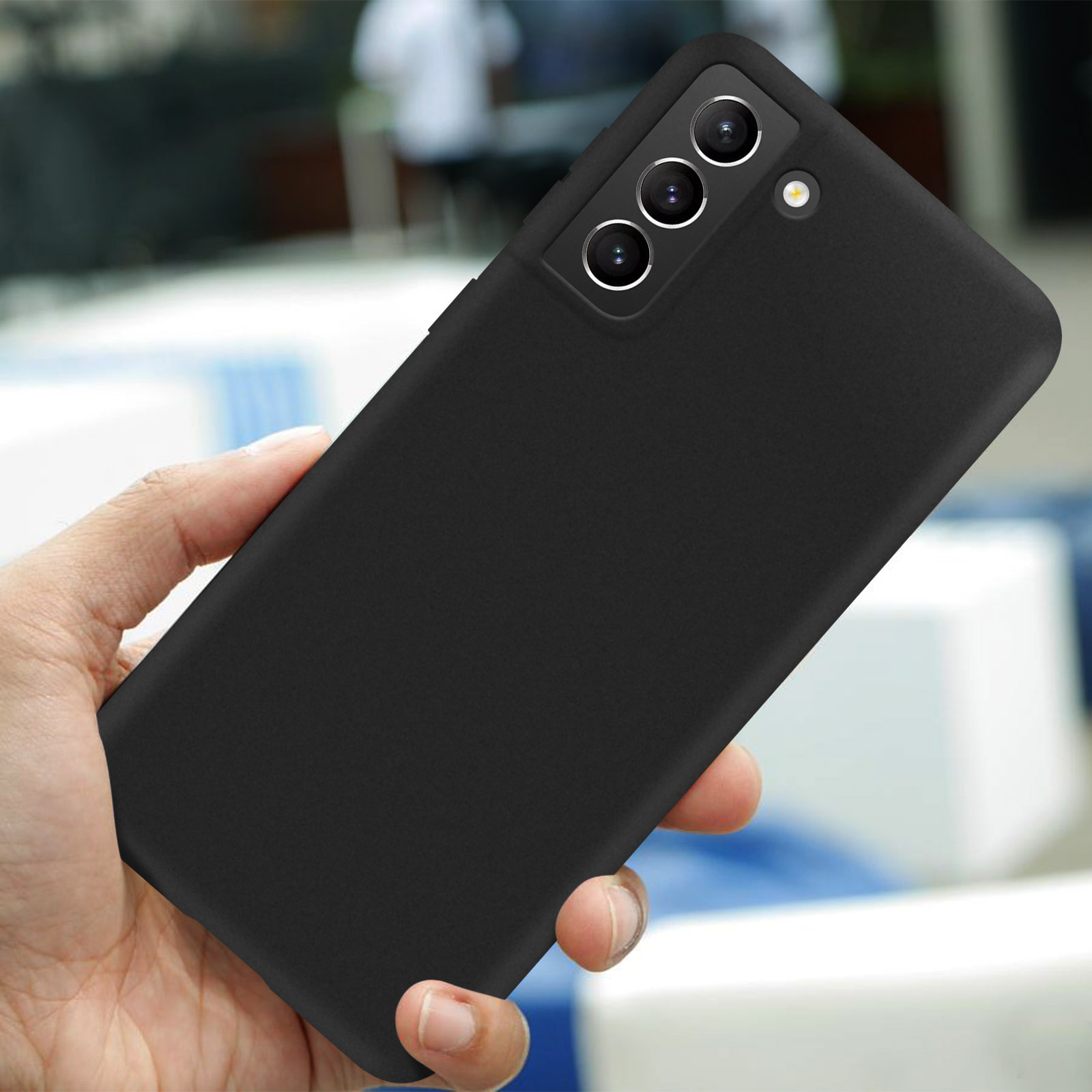 Une main tient un téléphone portable noir avec trois caméras et un flash.