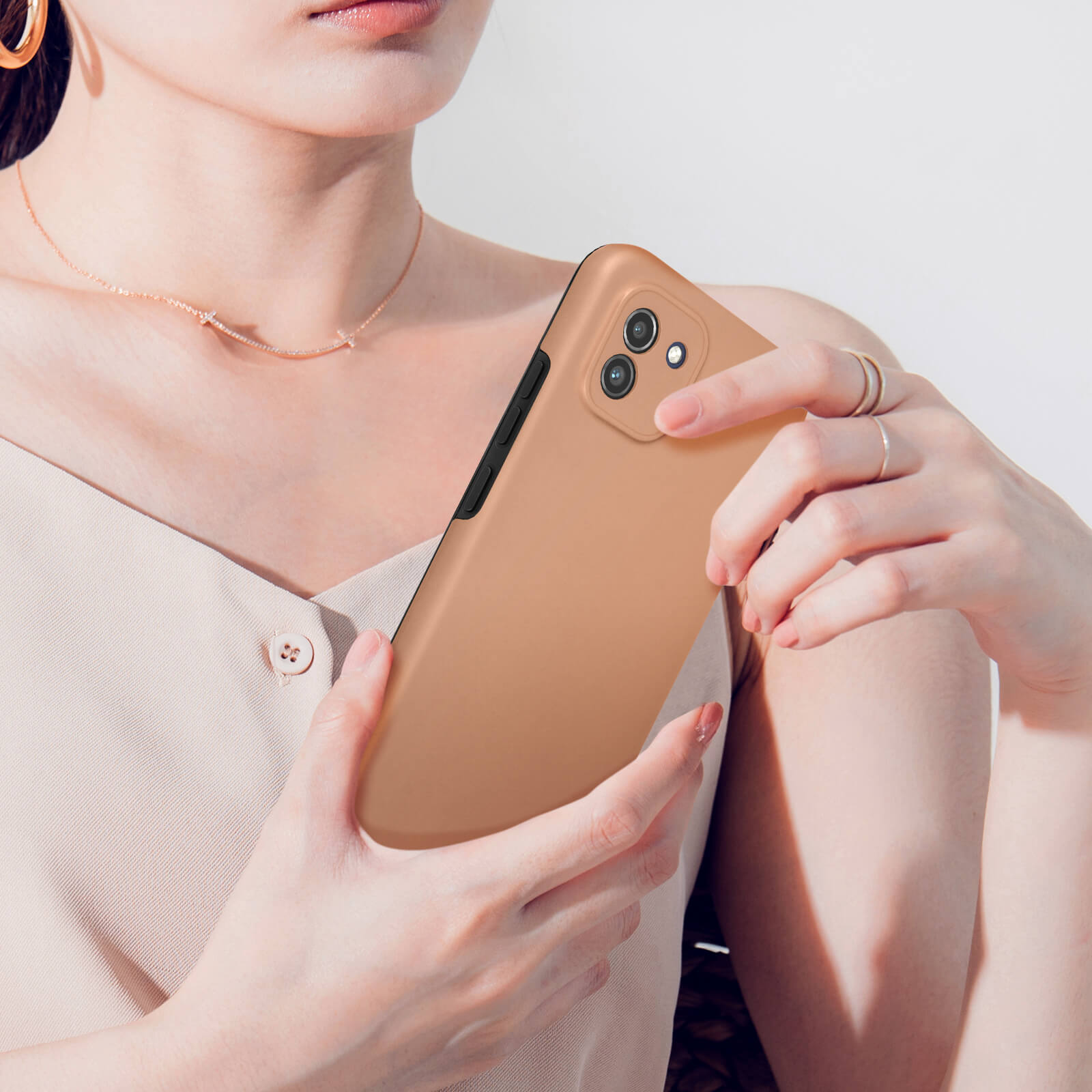 Una donna tiene uno smartphone color bronzo con tripla fotocamera.