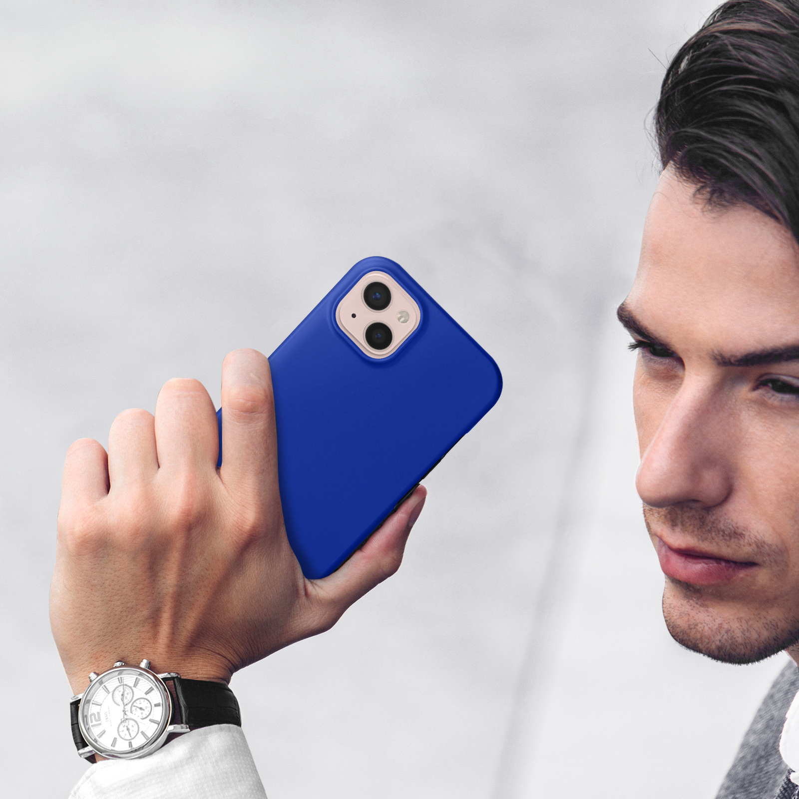 Uomo tiene smartphone blu con due fotocamere, indossa orologio.