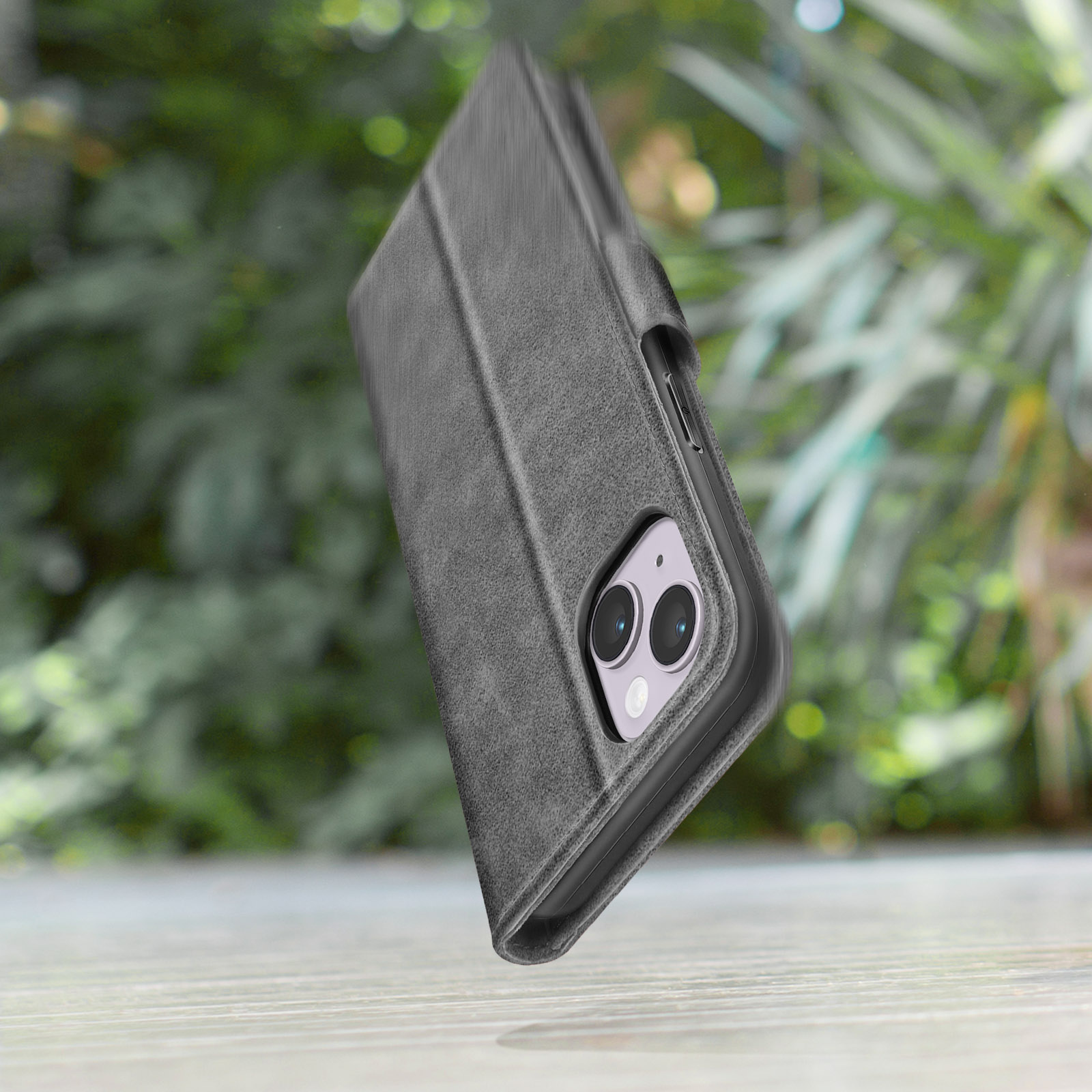 Custodia grigia per telefono con due fotocamere su tavolo di legno davanti al verde.