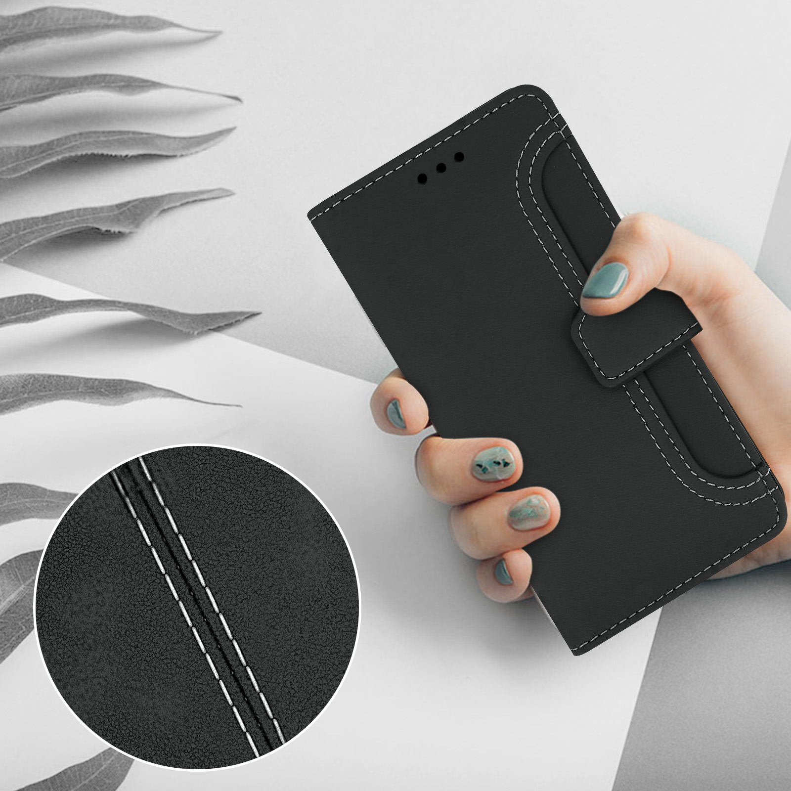 Une main tient un étui de téléphone noir avec surpiqûres blanches. Gros plan sur la texture.