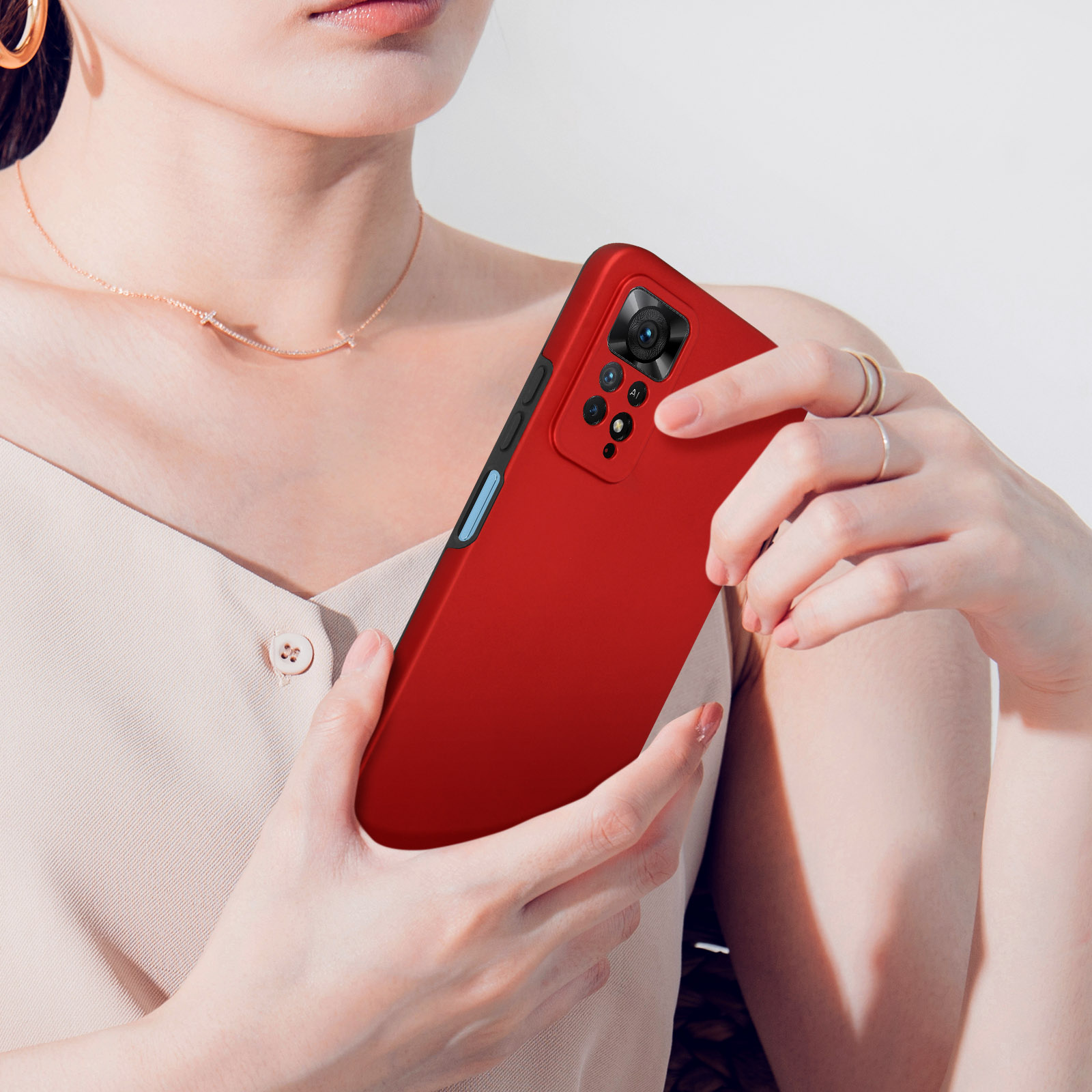 Une femme tient un téléphone rouge avec un système à quatre caméras et logo IA.
