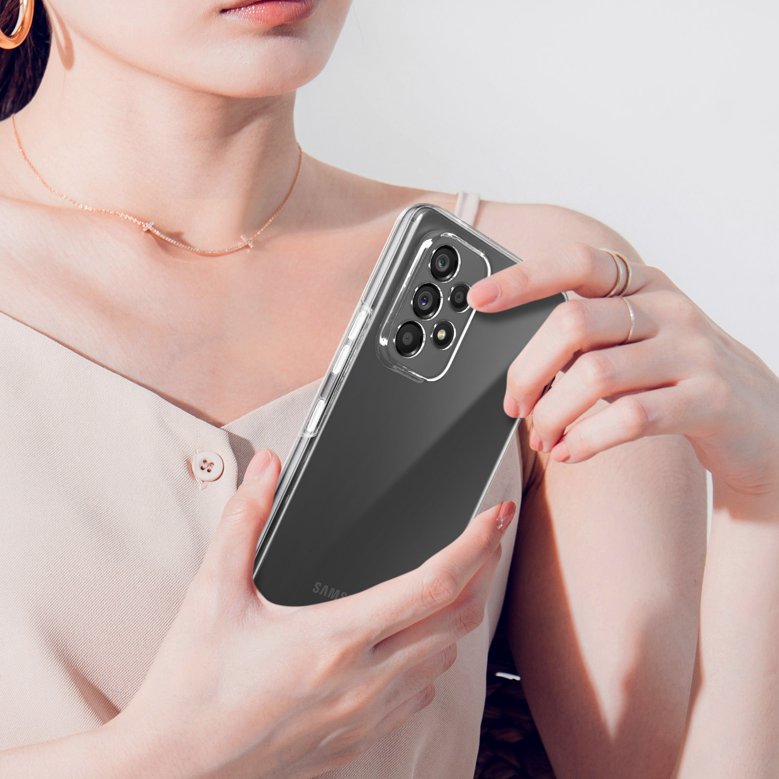 Une personne tenant un smartphone dans un étui transparent, caméras à l'arrière.