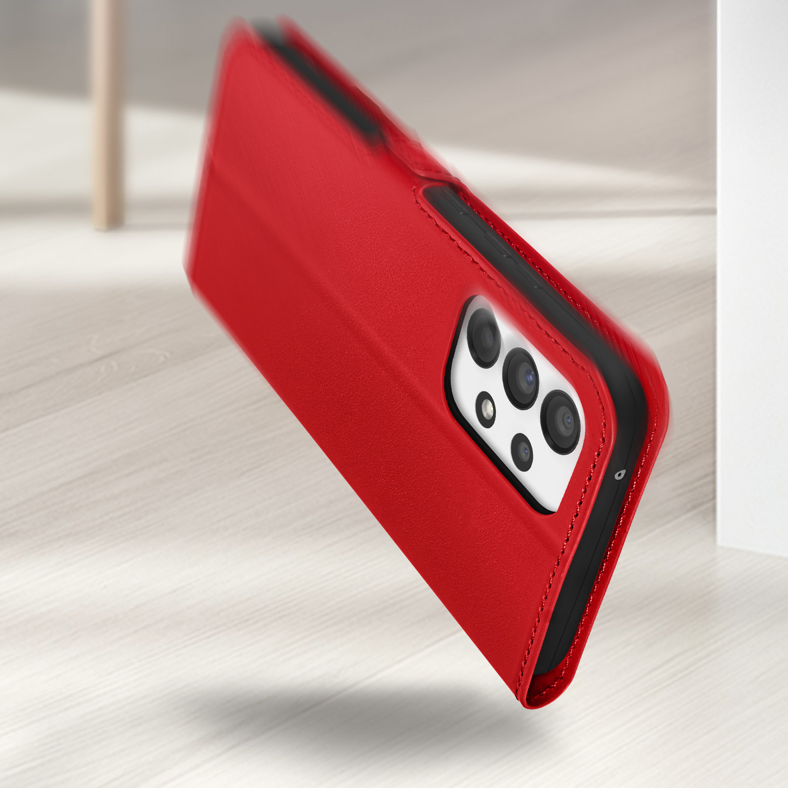 Un étui de téléphone rouge repose sur un sol en bois. La caméra est visible.