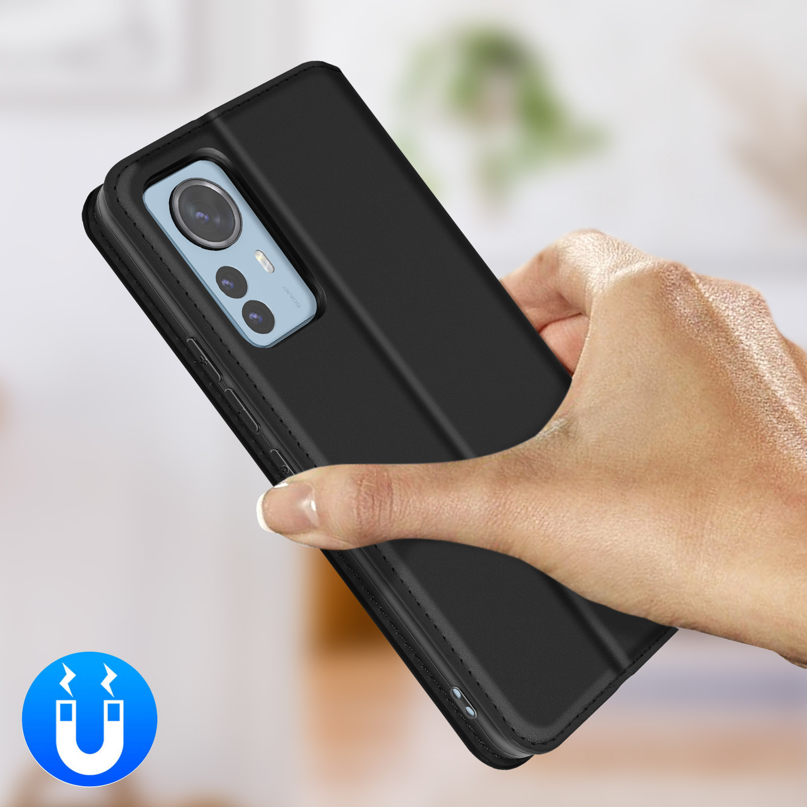 Una mano tiene un telefono nero con un array di fotocamere e un simbolo magnetico.