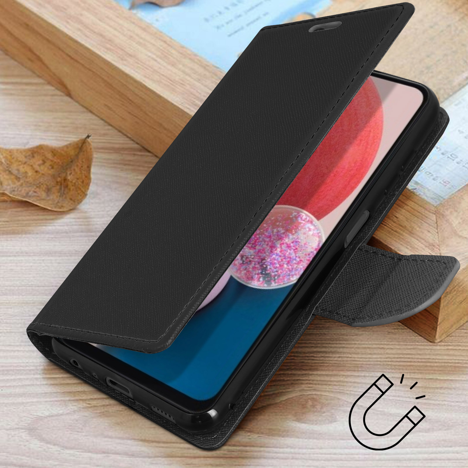 Funda negra tipo libro para teléfono sobre superficie de madera con hoja seca e icono imán.